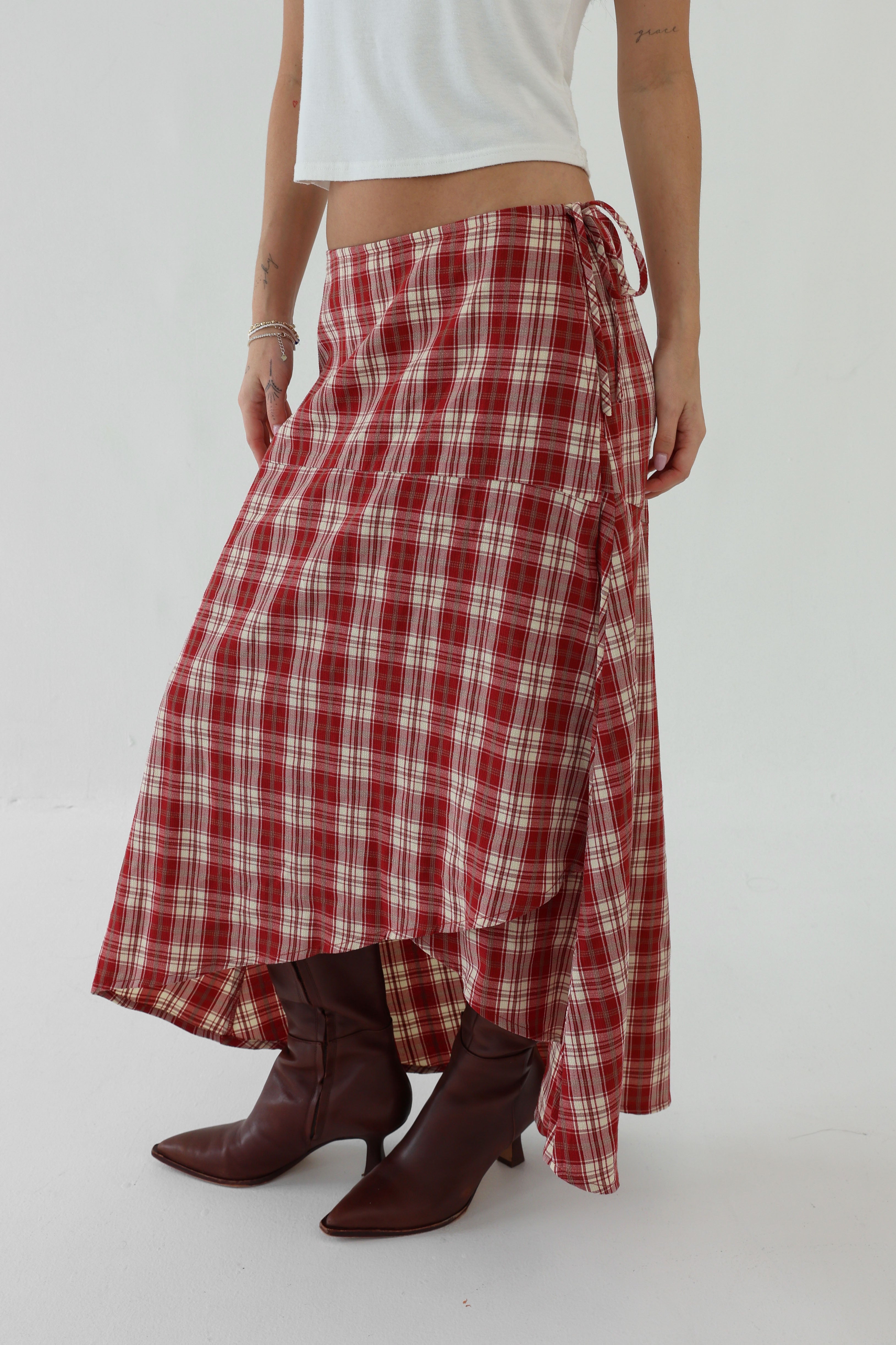 Person wearing a red plaid skirt and brown boots on a white background