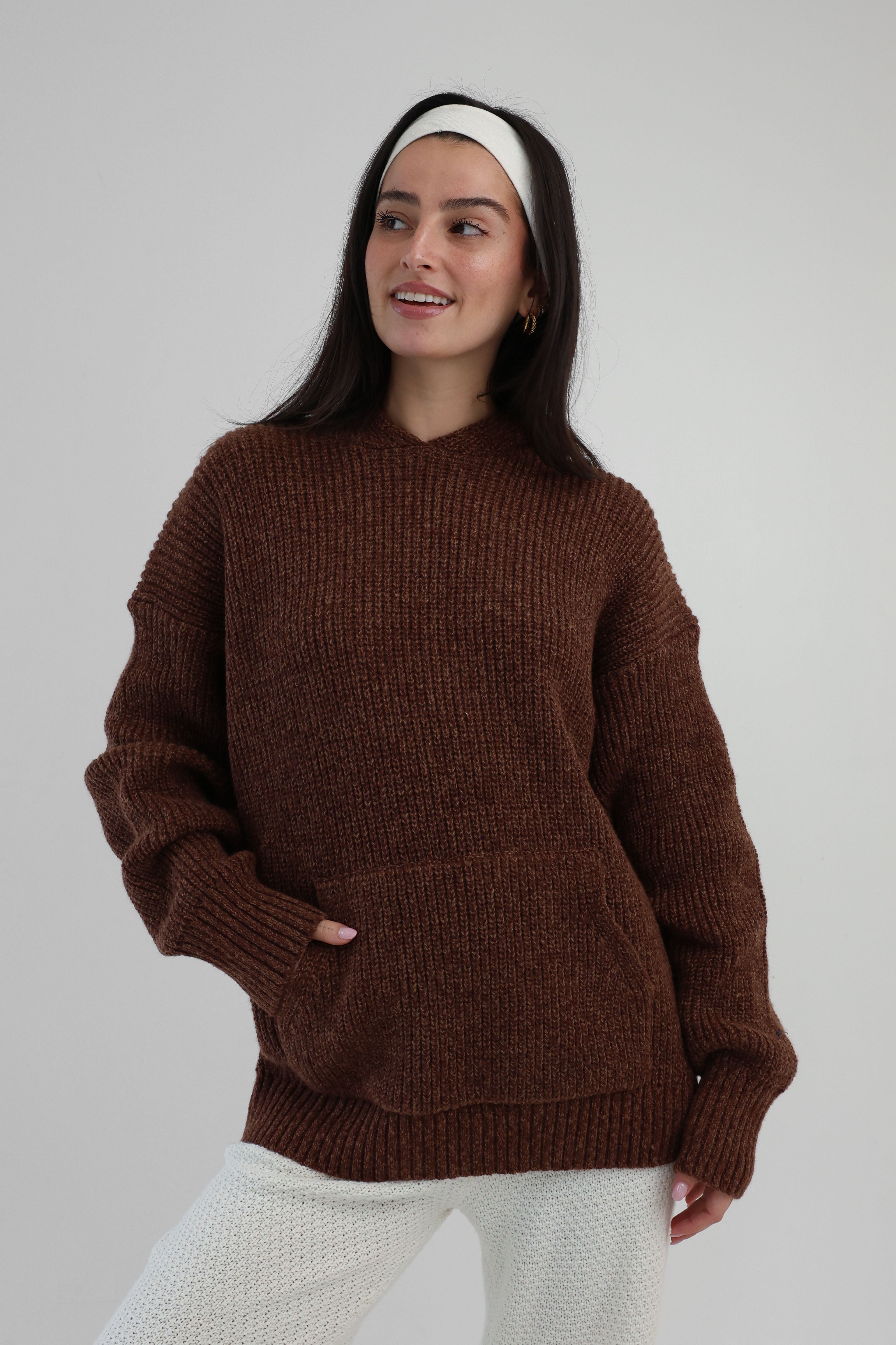 Woman wearing a brown sweater against a plain background