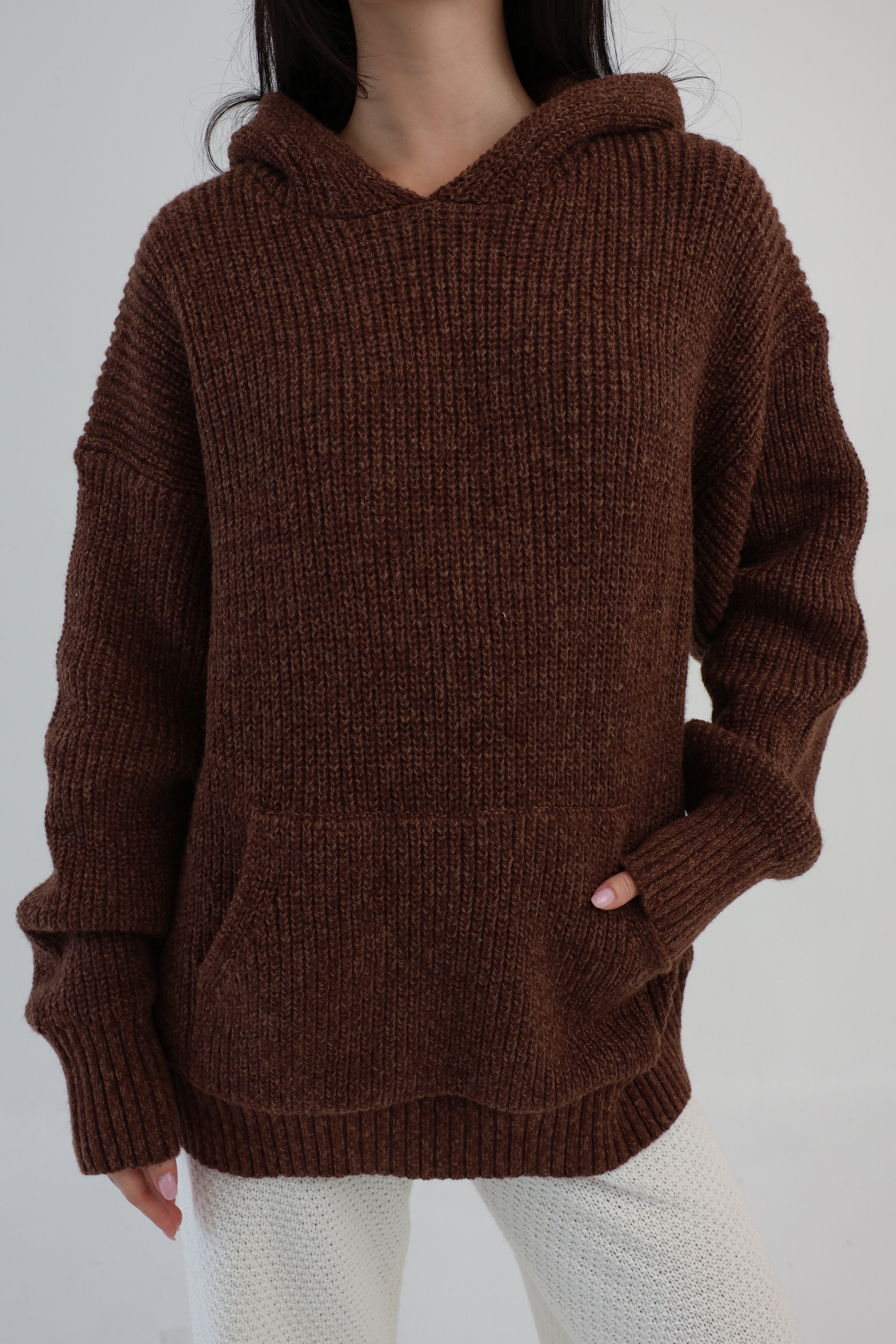 Brown knitted hoodie worn by a person on a white background
