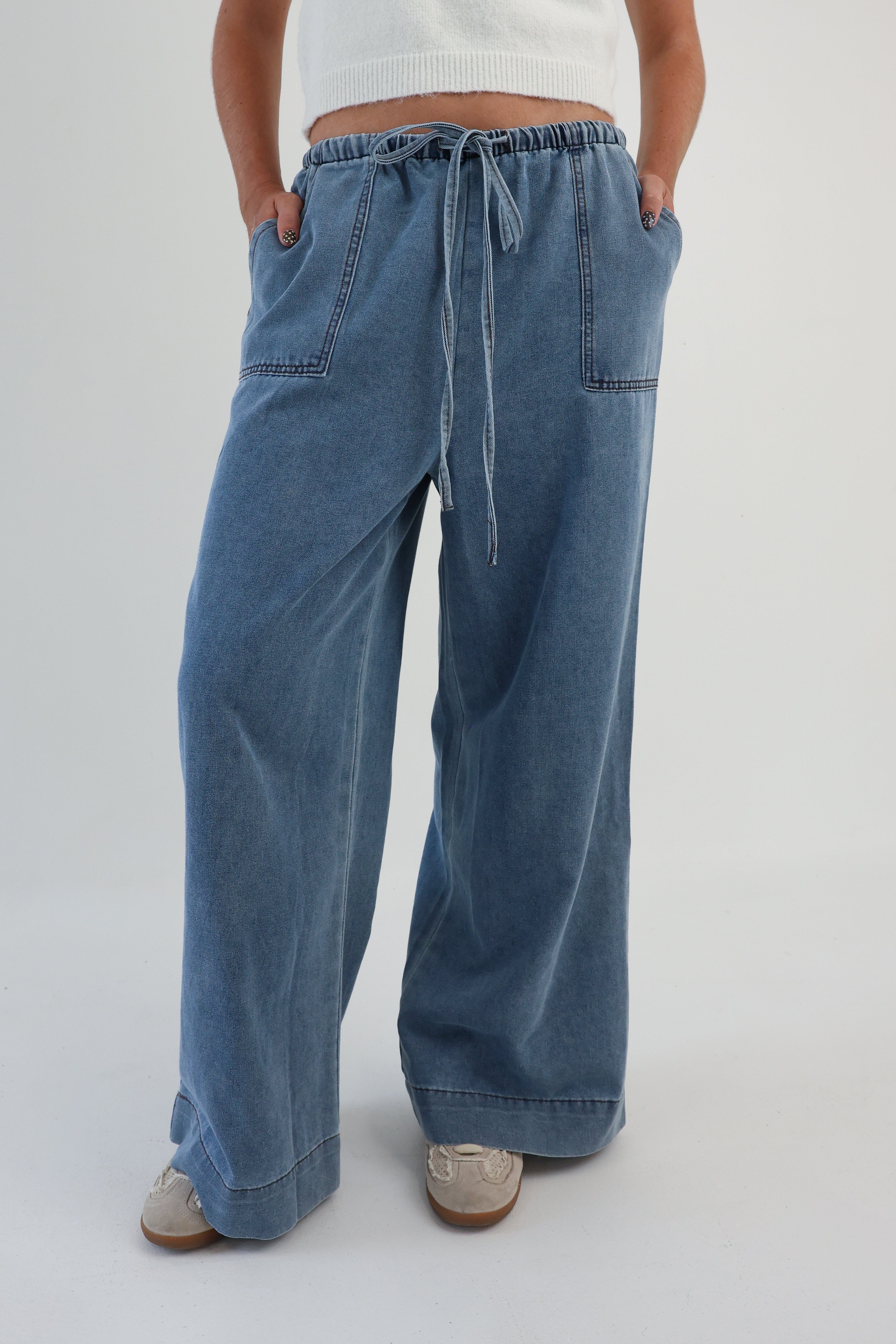 Person wearing blue wide-leg jeans on a plain background