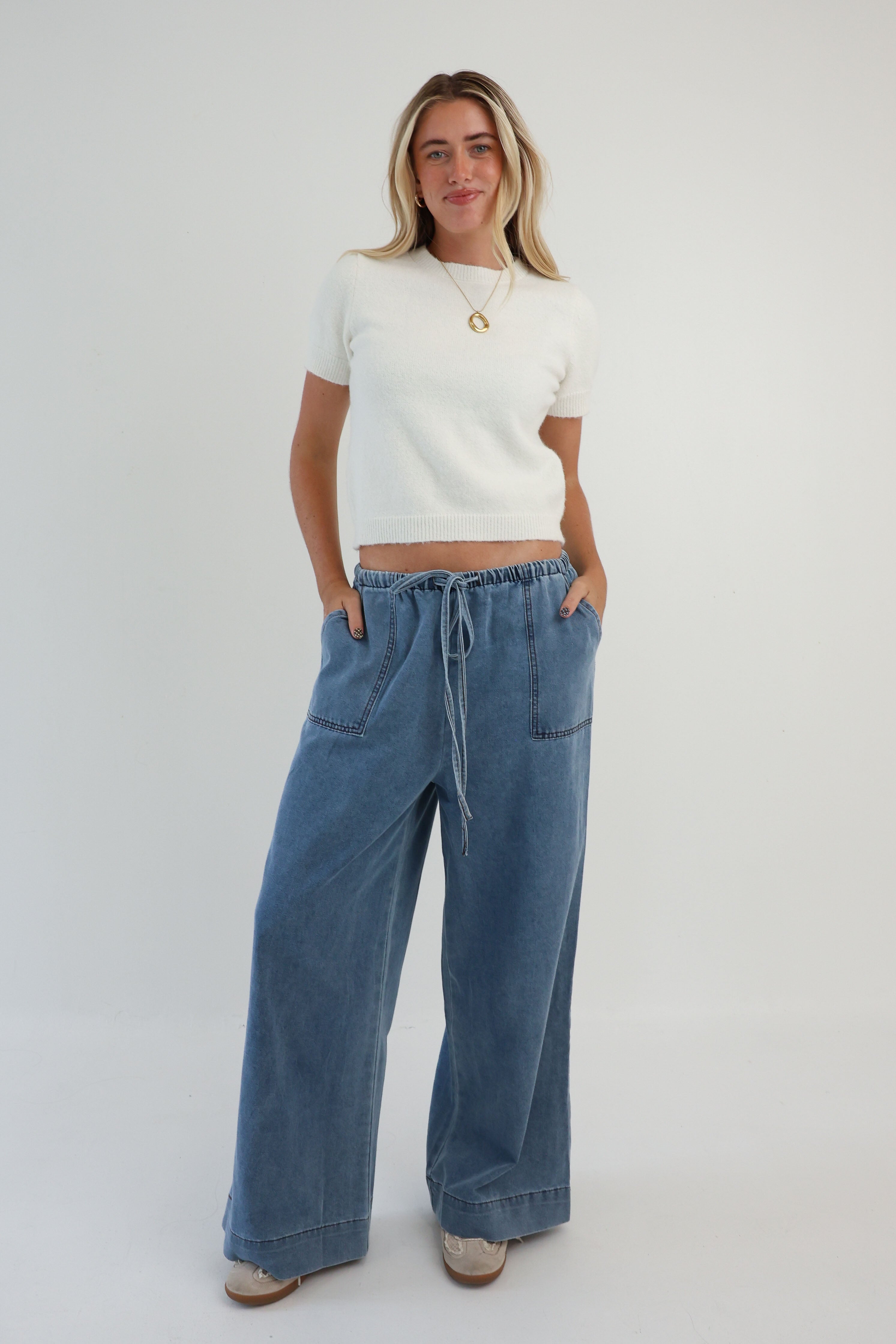 Woman wearing a white top and blue jeans on a plain background