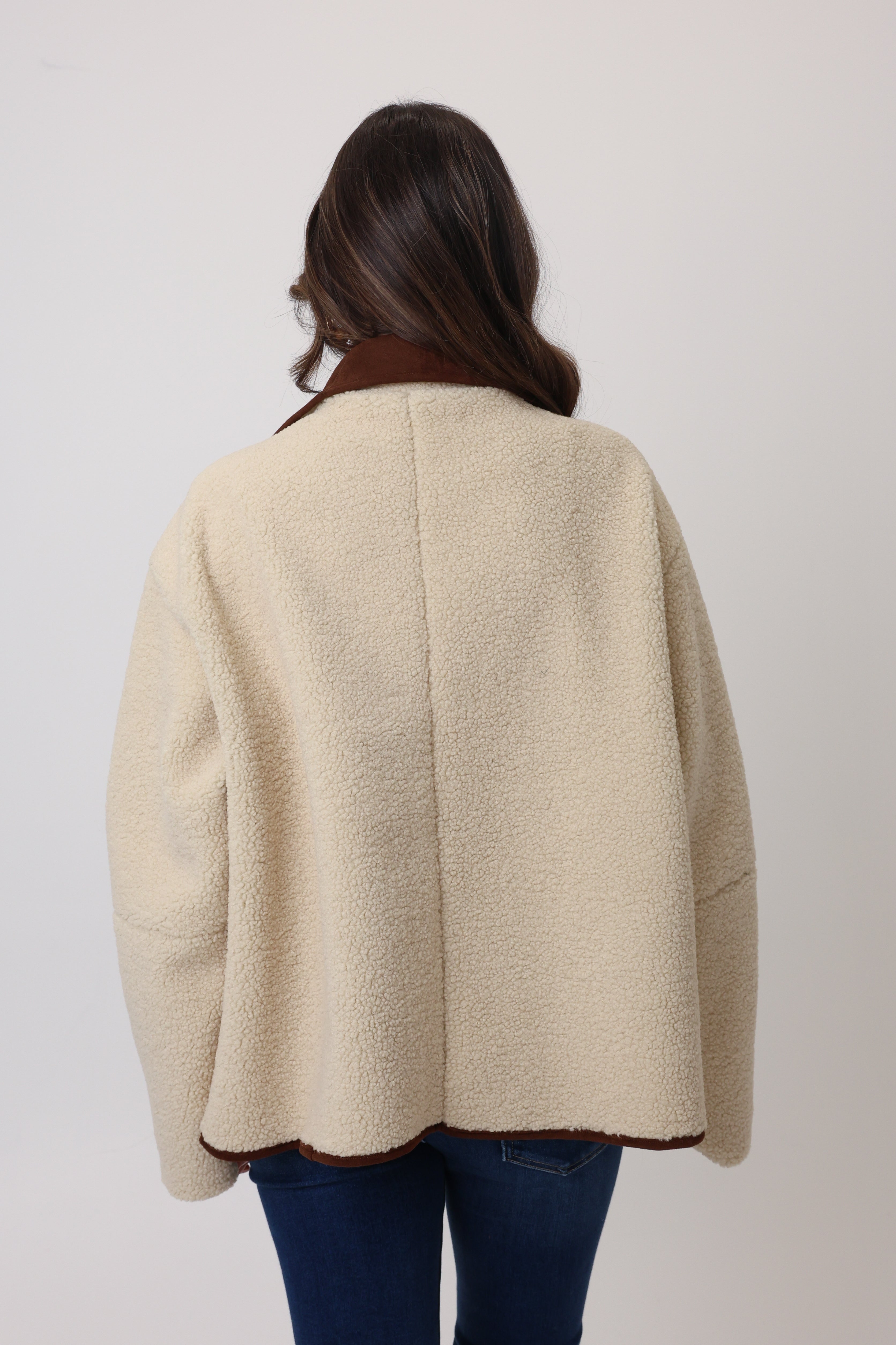 Person wearing a beige coat with a plain background