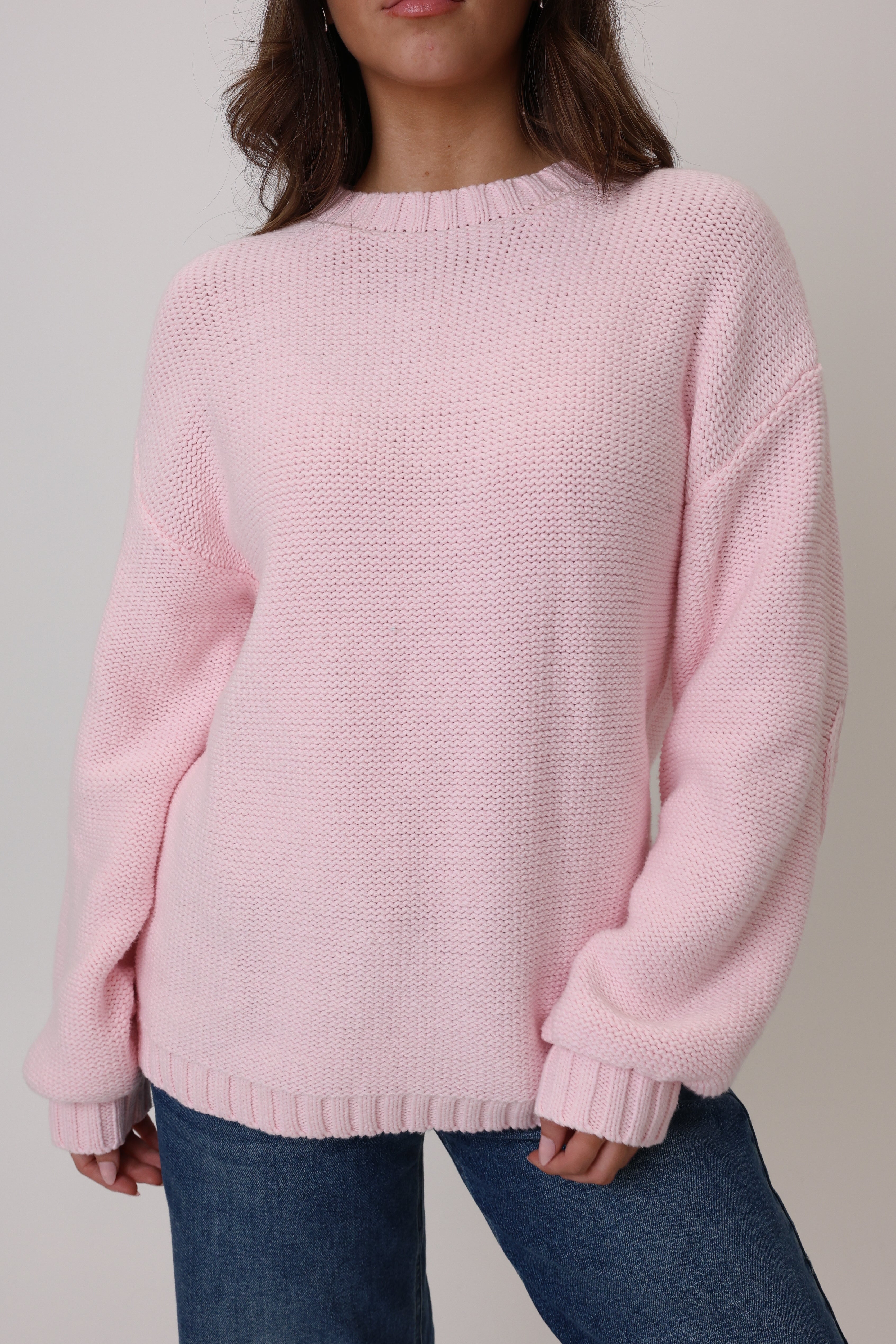 Person wearing a pink sweater against a neutral background