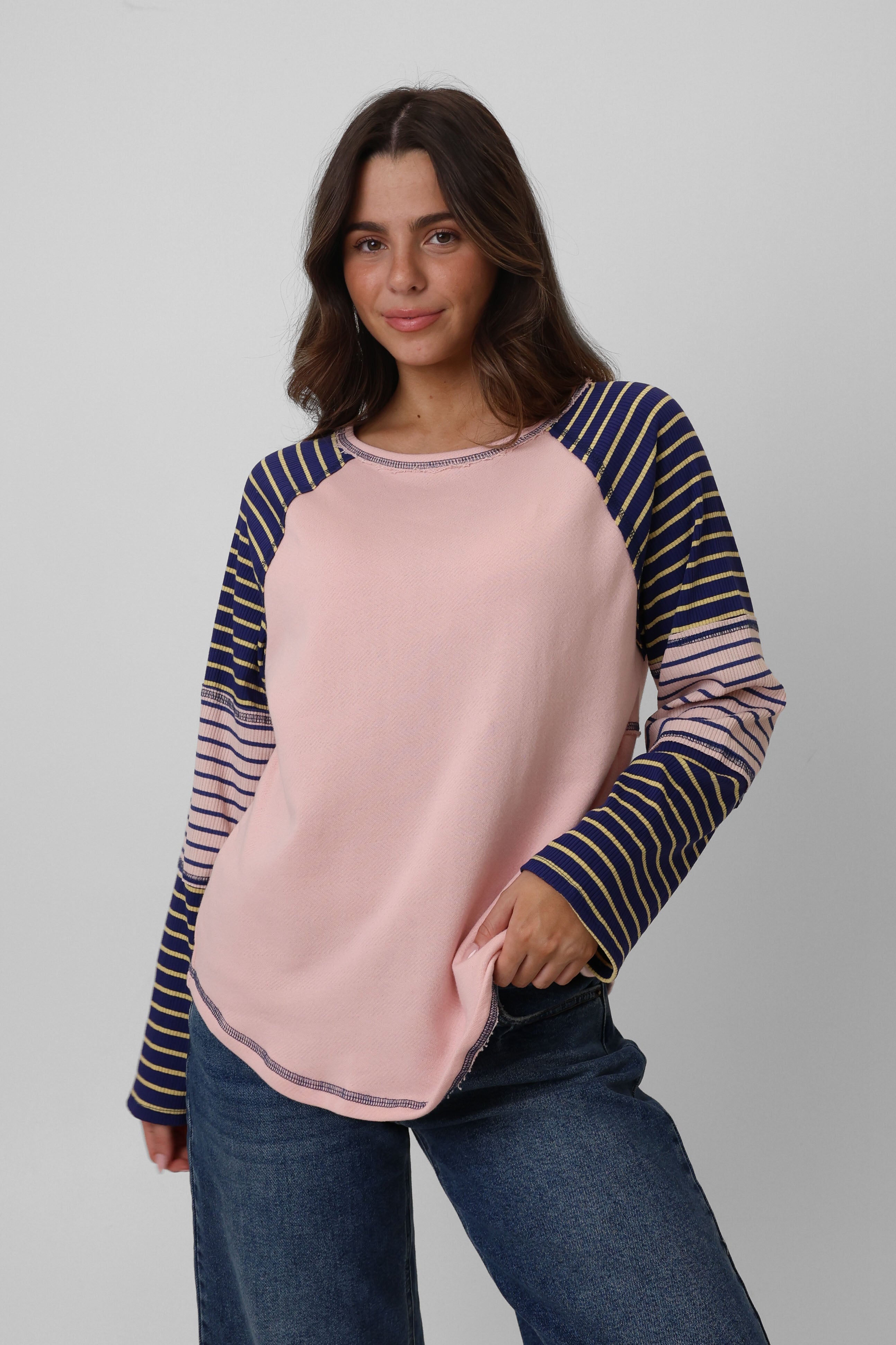Woman wearing a pink and navy striped long-sleeve top against a gray background