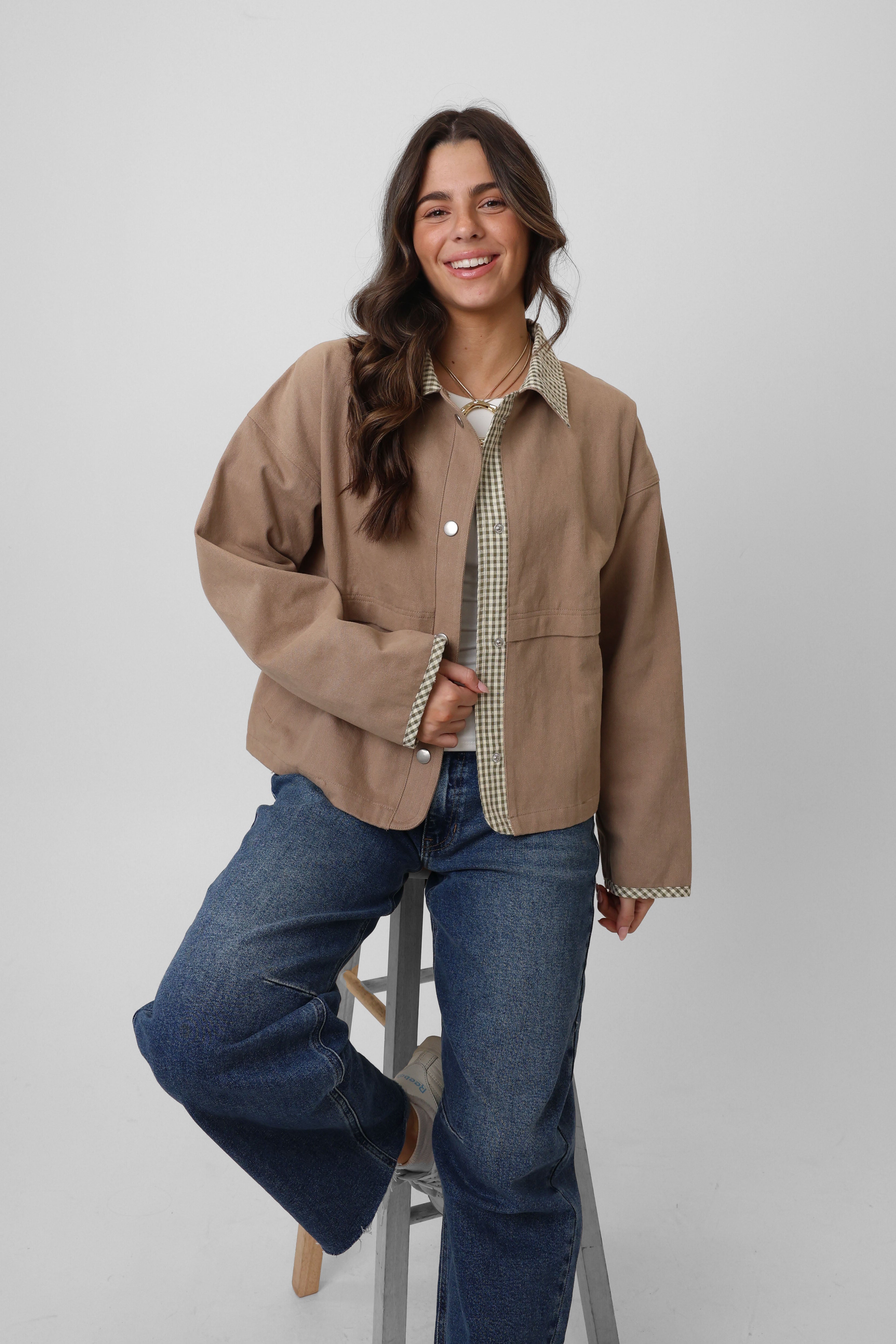 Woman wearing a beige jacket and blue jeans on a white background