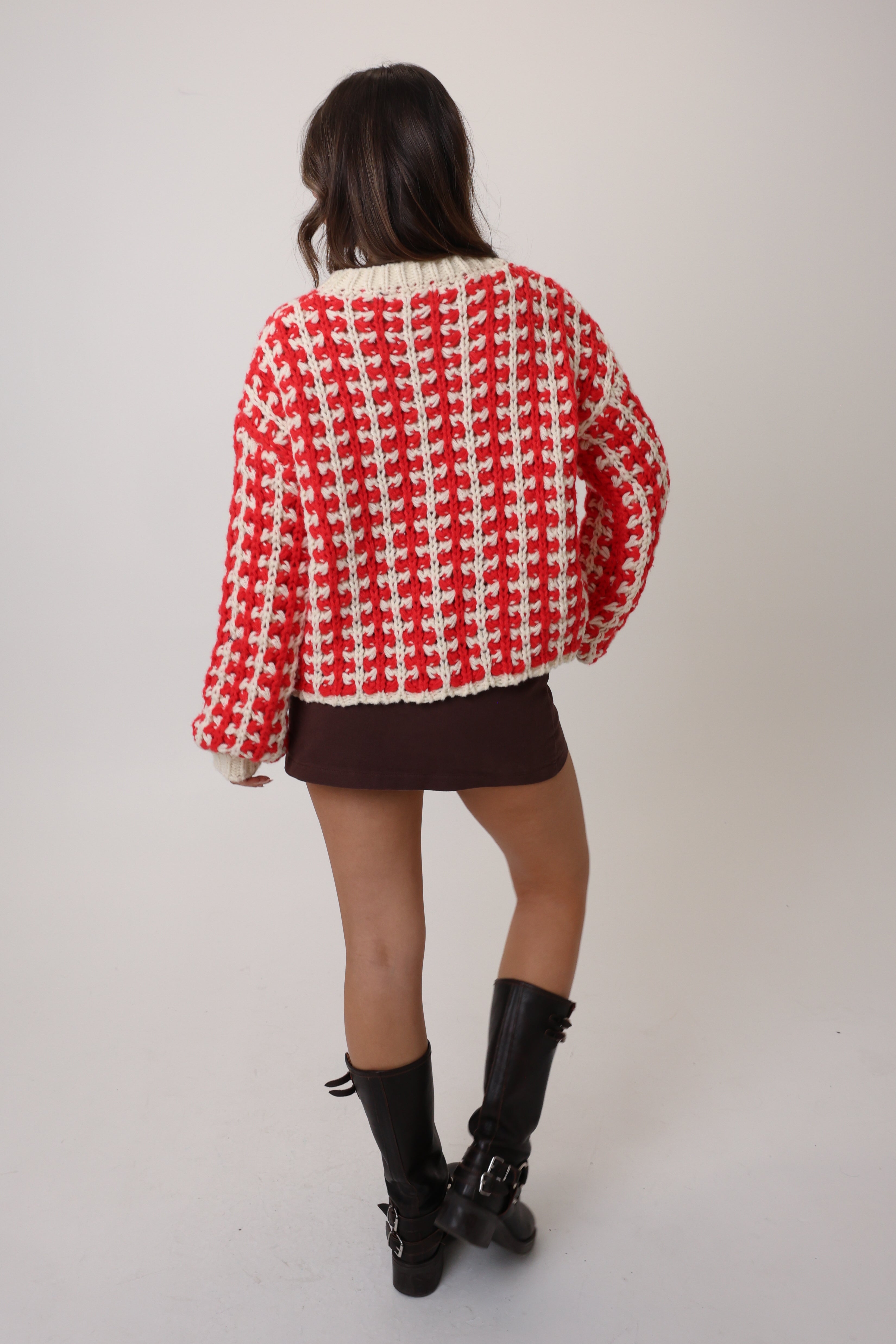 Person wearing a red and white checkered sweater on a plain background