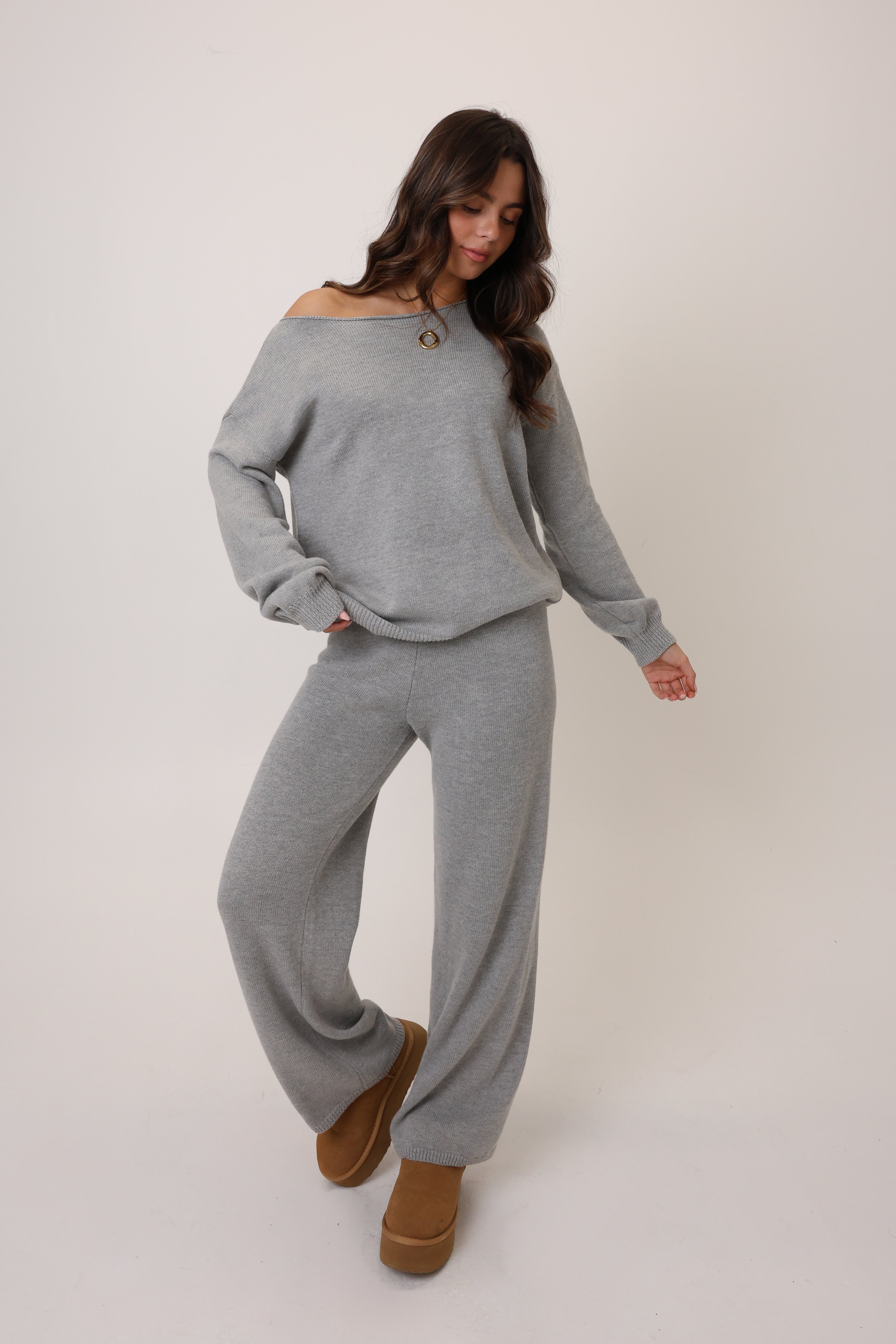 Woman wearing a gray sweater and pants set on a white background