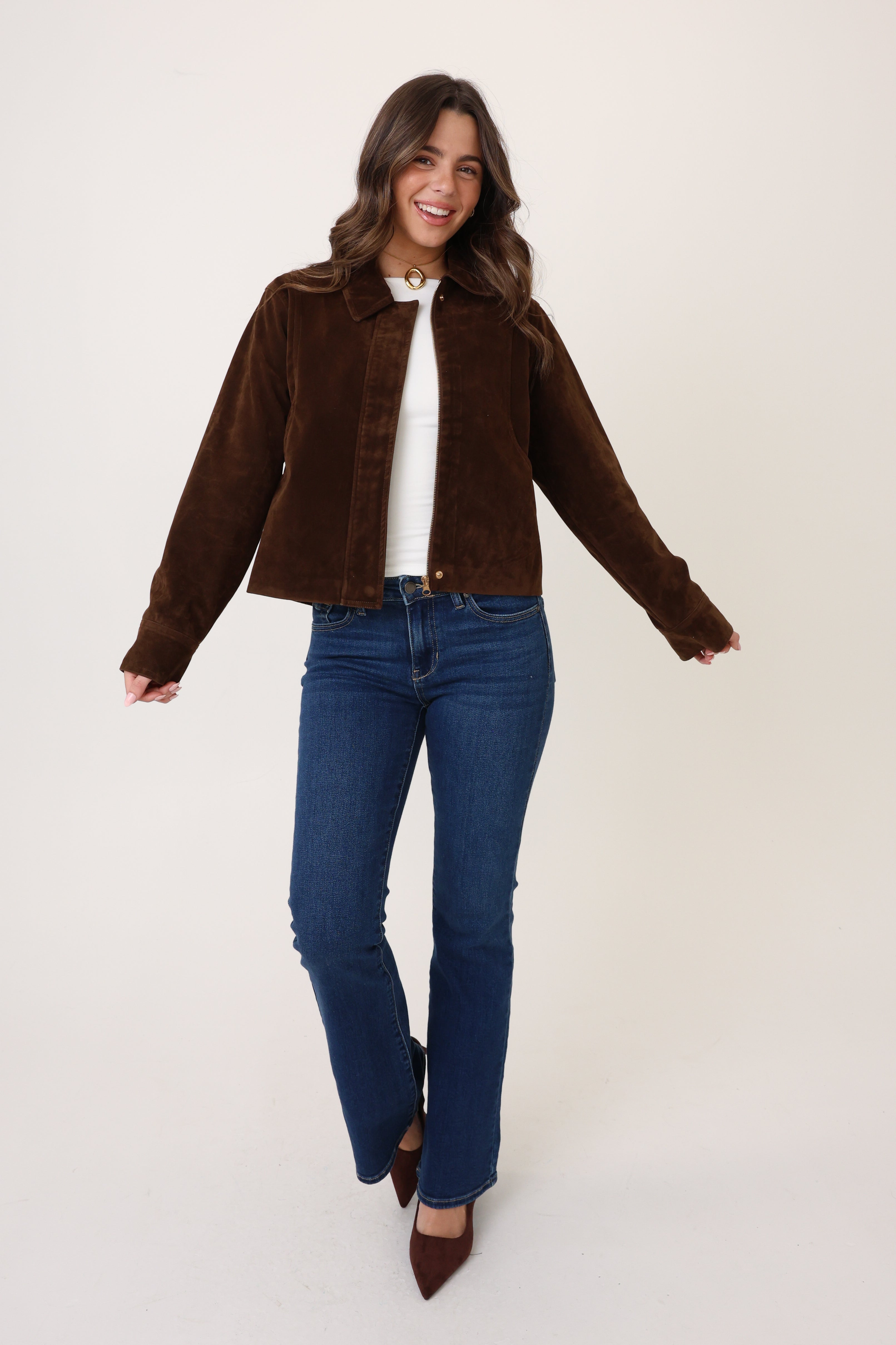 Woman wearing a brown jacket and blue jeans on a white background