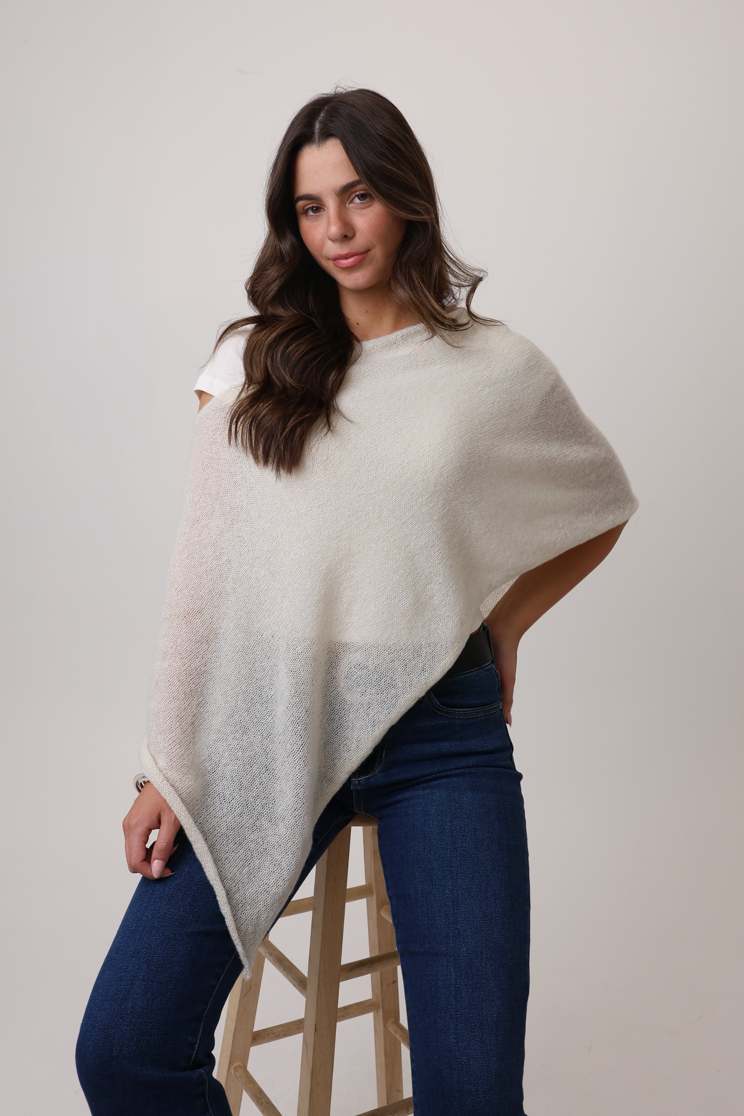Woman wearing a white and gray gradient poncho with a plain background