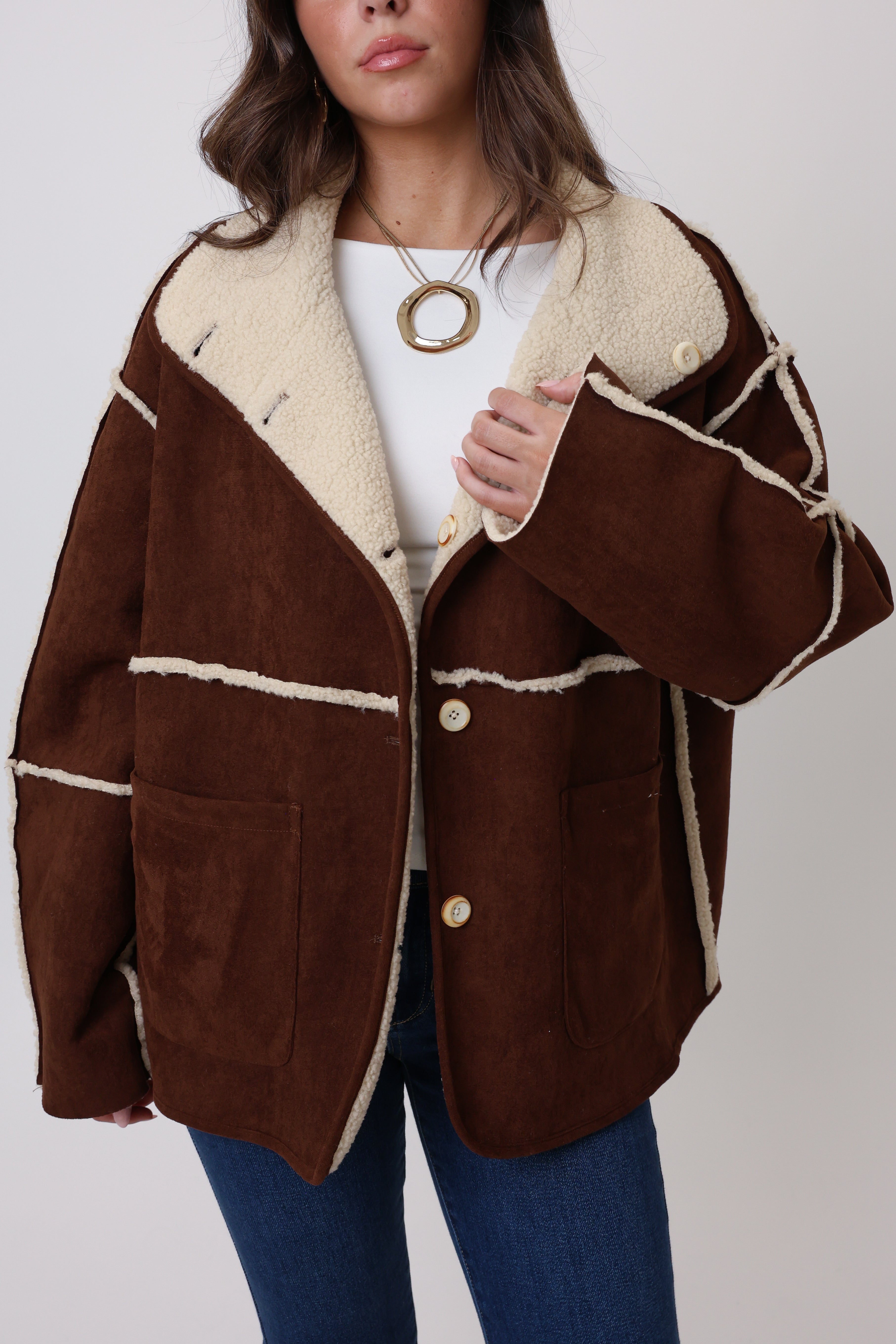 Brown jacket with white trim worn by a person on a plain background