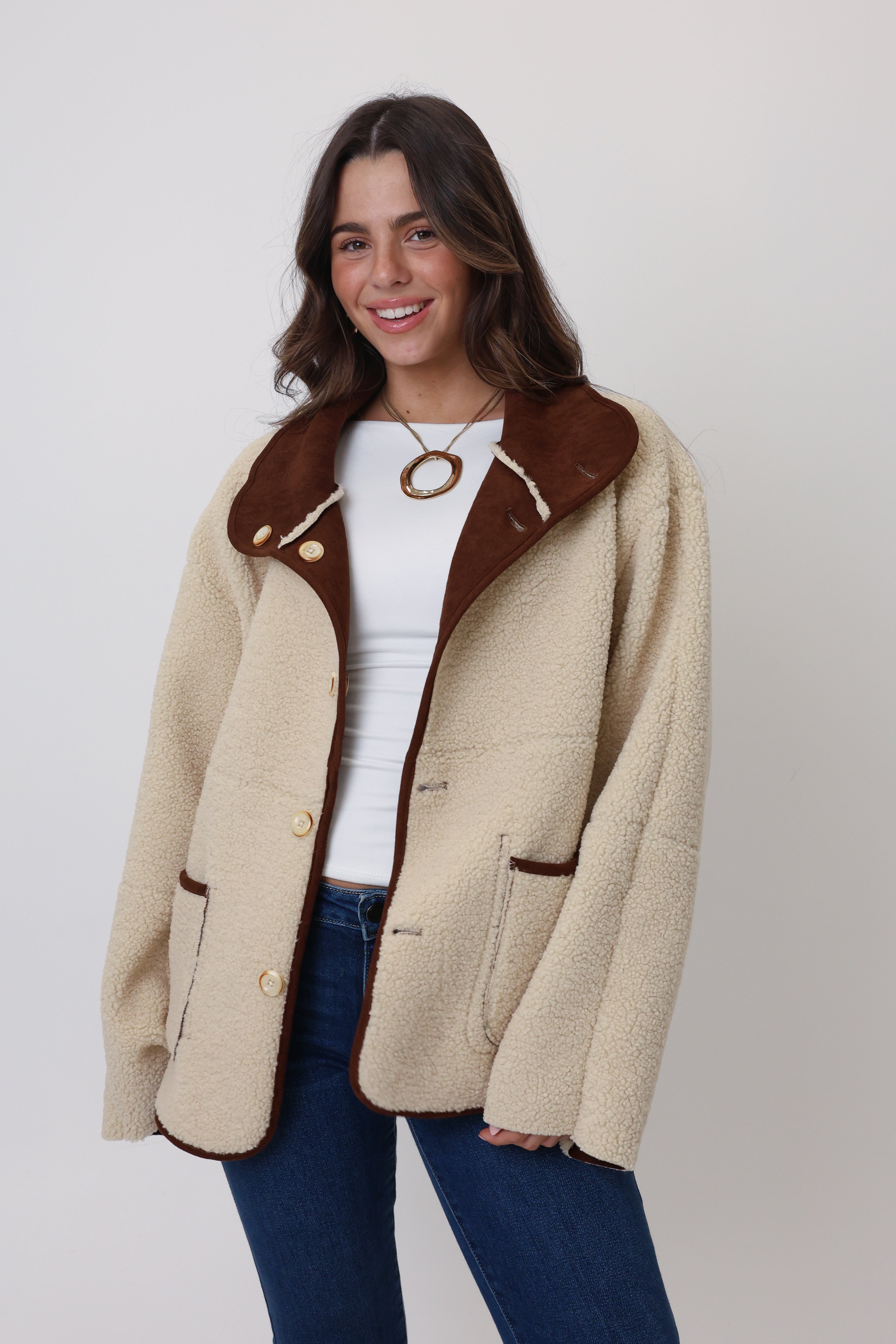 Woman wearing a beige jacket with brown accents on a white background