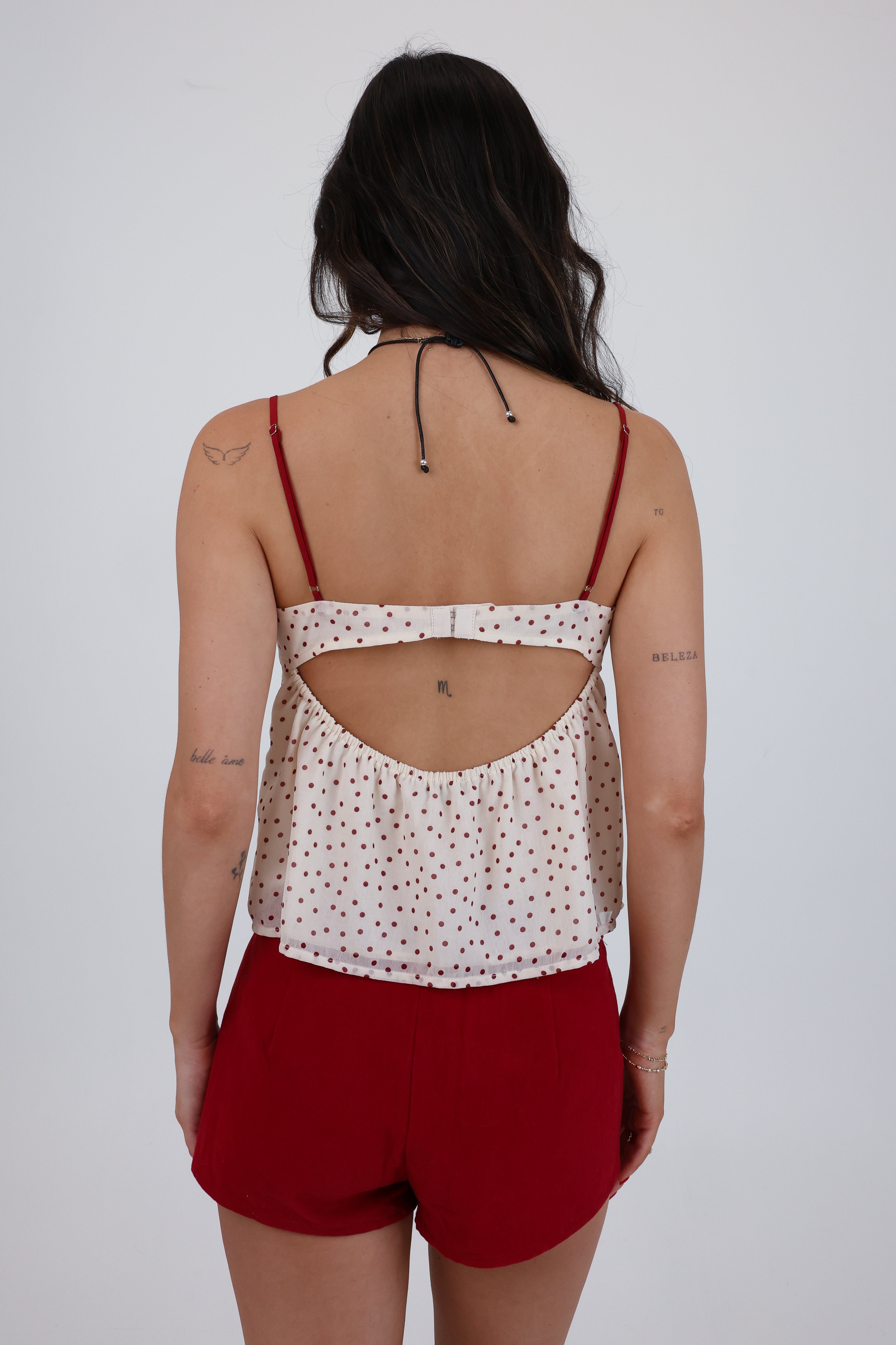 Person wearing a polka dot top with cut-out design and red shorts on a white background