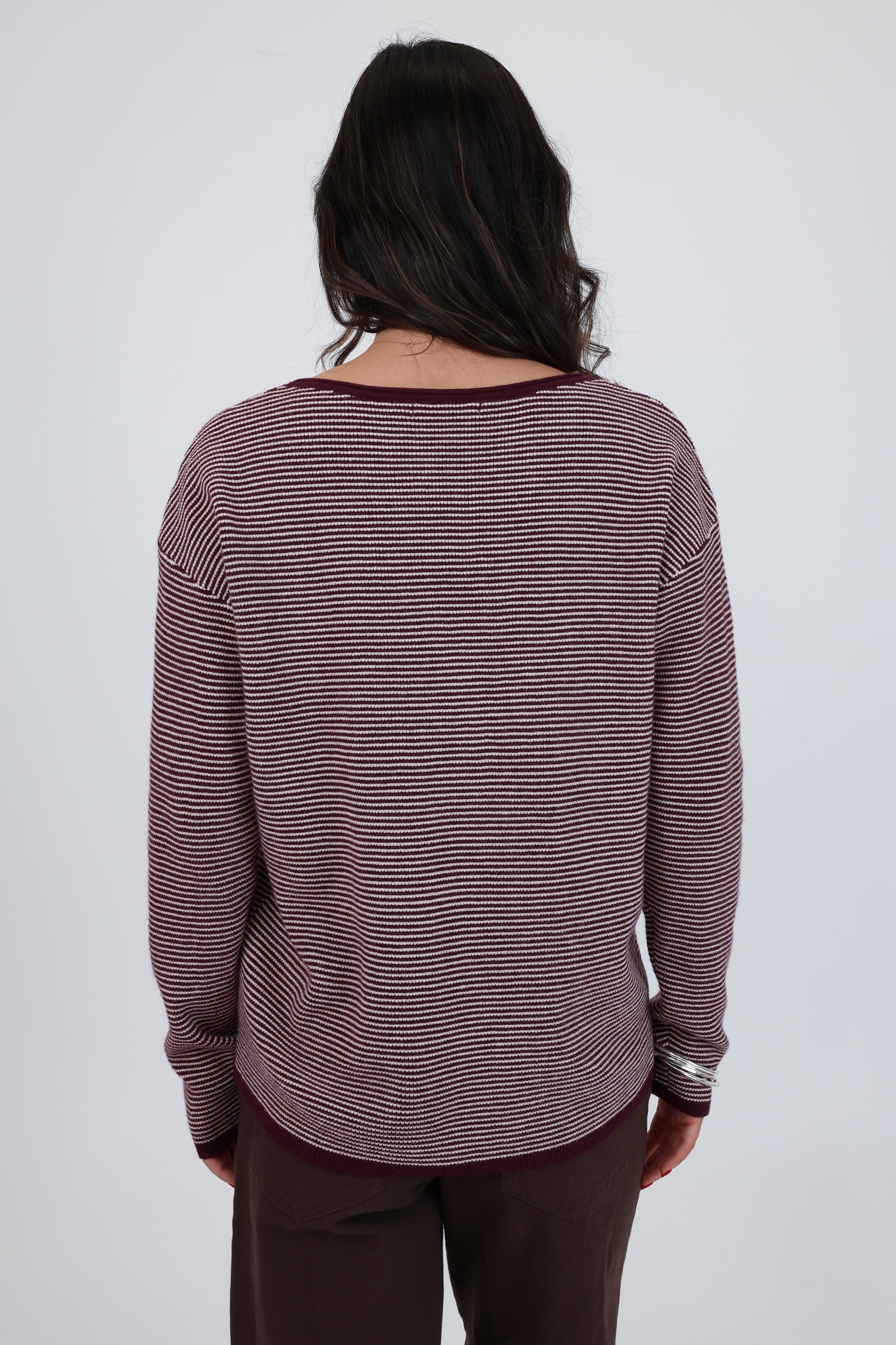 Person wearing a maroon and white striped sweater on a plain background