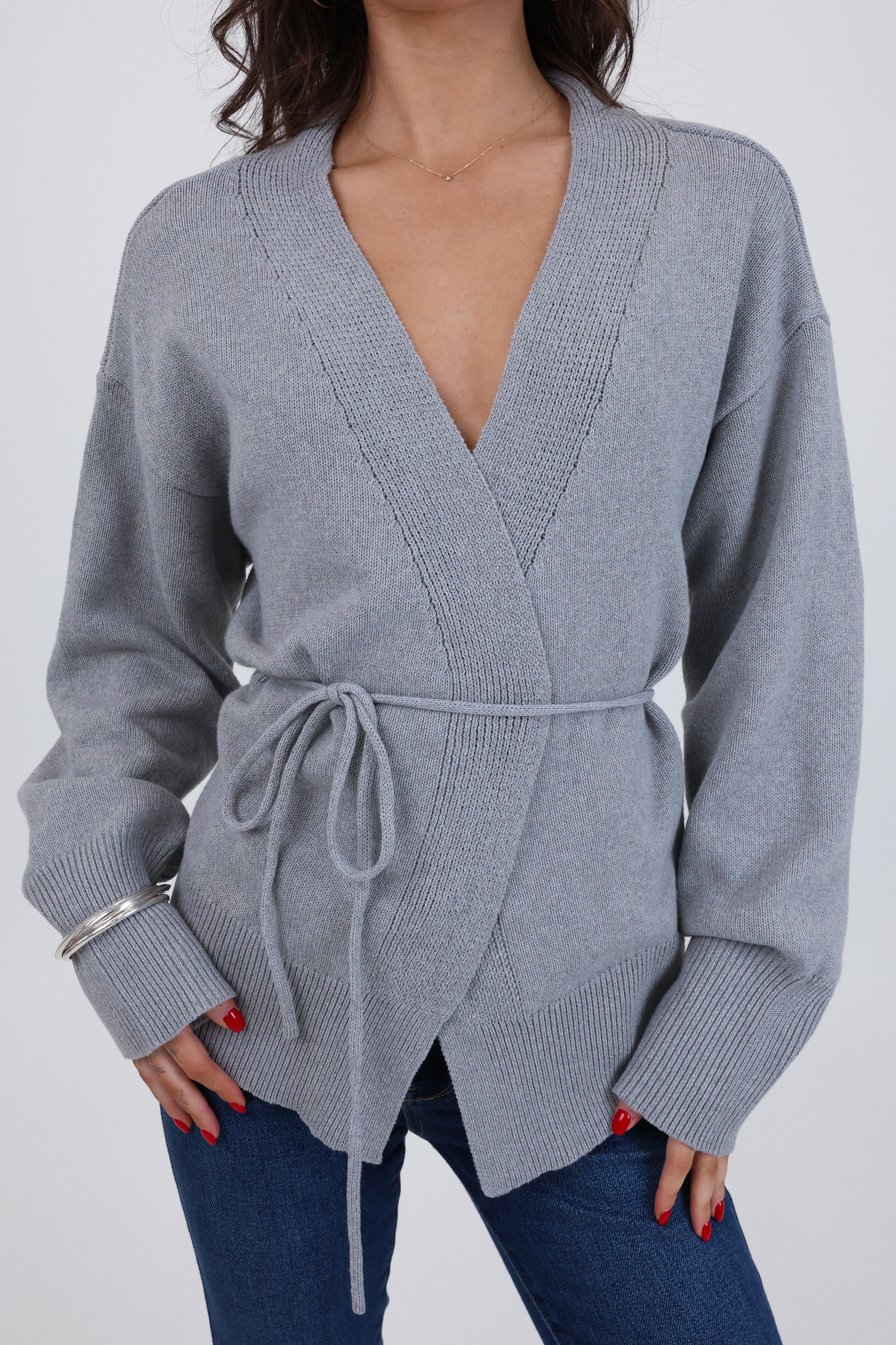 Gray wrap sweater worn by a person on a white background