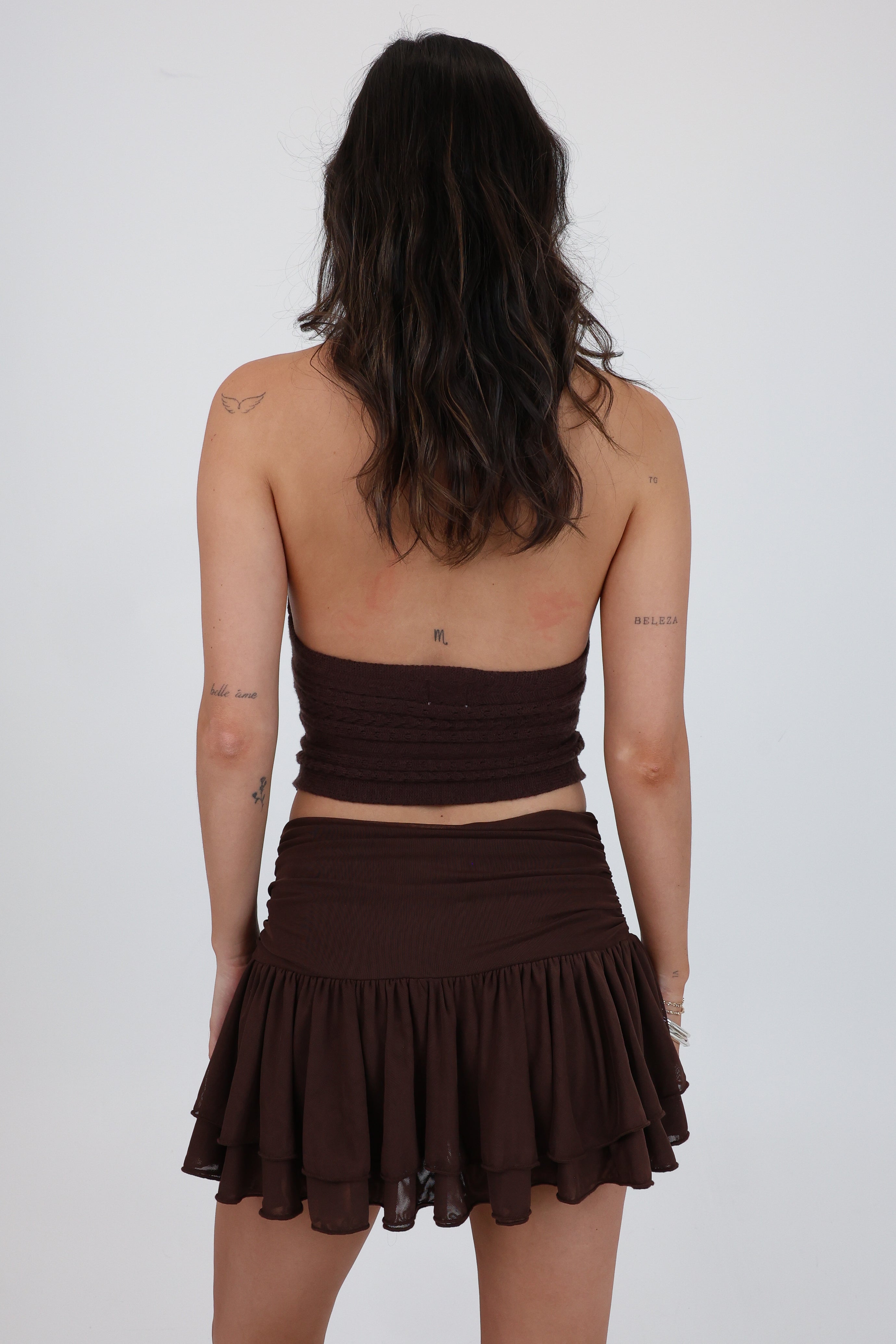 Person wearing a brown two-piece outfit on a white background