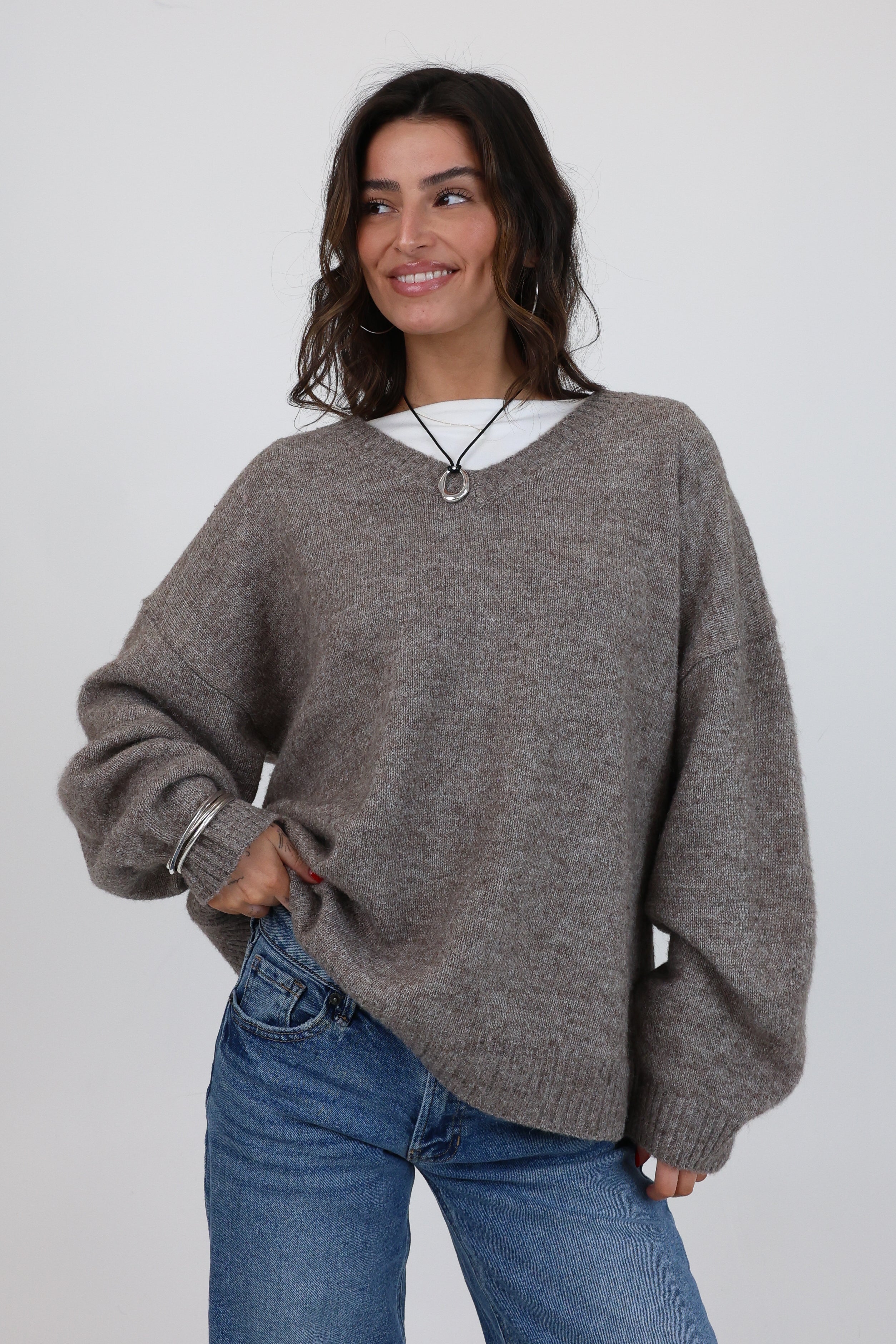 Woman wearing a gray sweater and blue jeans on a white background