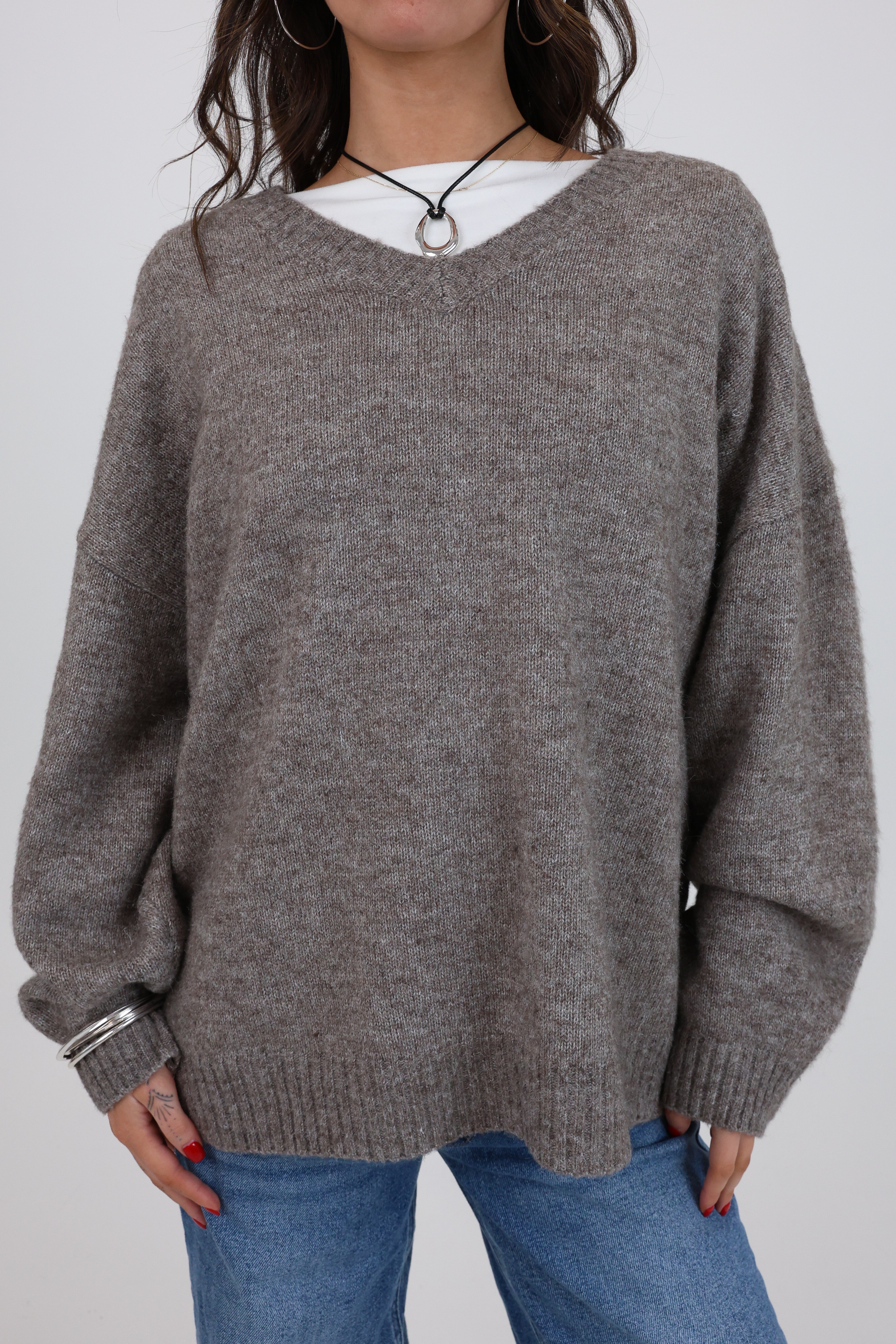 Person wearing a gray sweater and blue jeans on a plain background