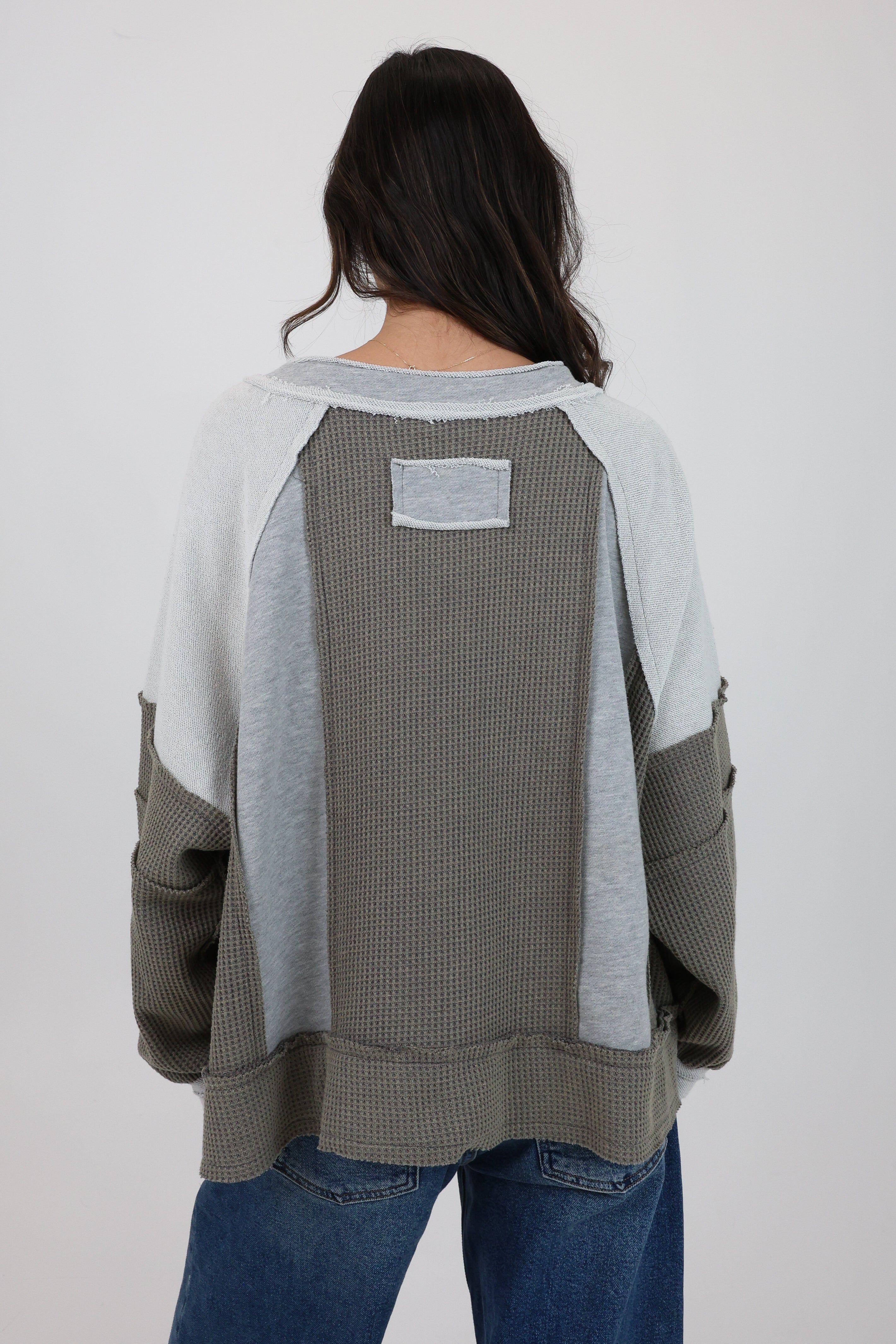 Person wearing a gray and white sweater with a plain background