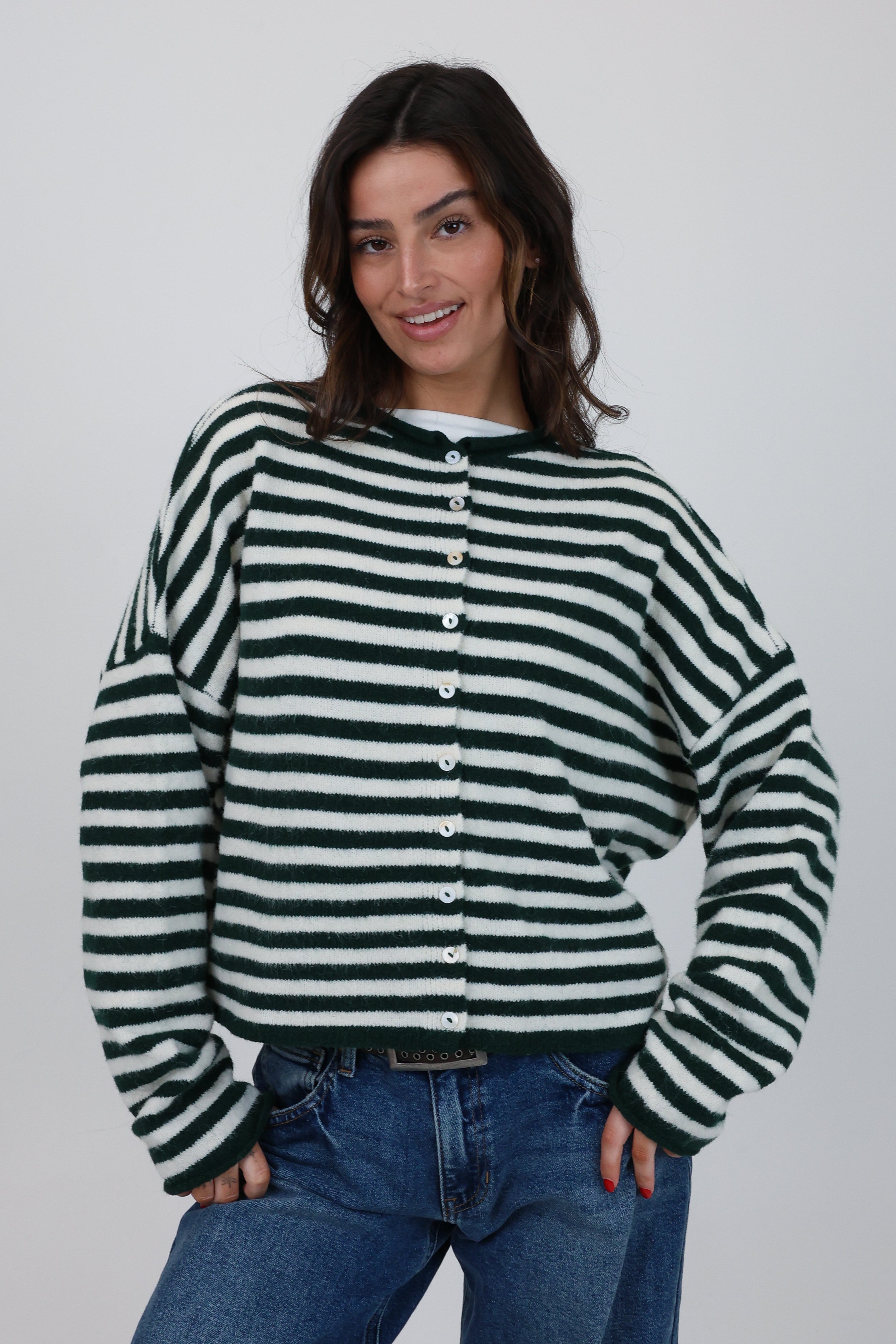 Woman wearing a green and white striped sweater with a plain background
