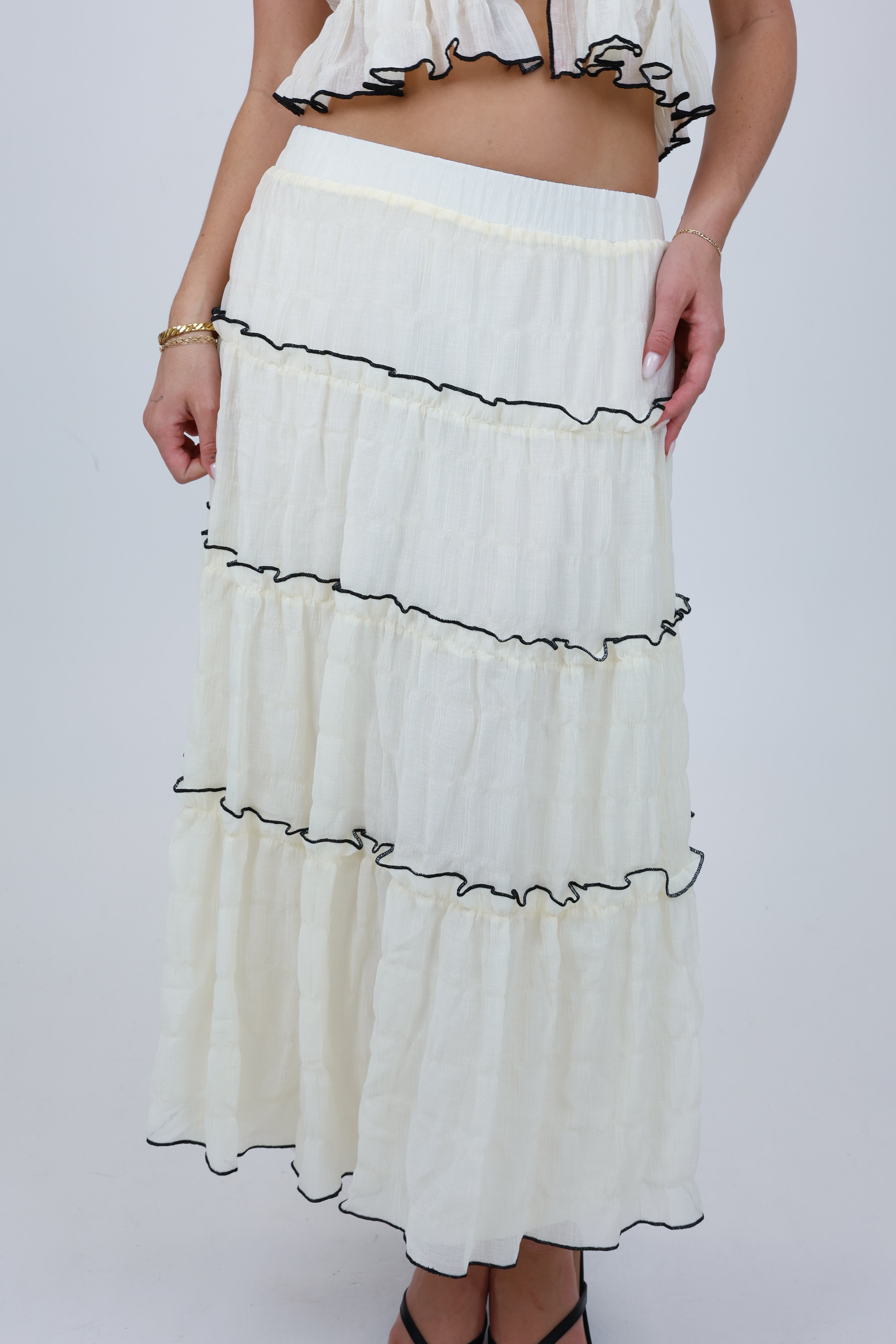 White skirt with black ruffled trim worn by a person on a white background