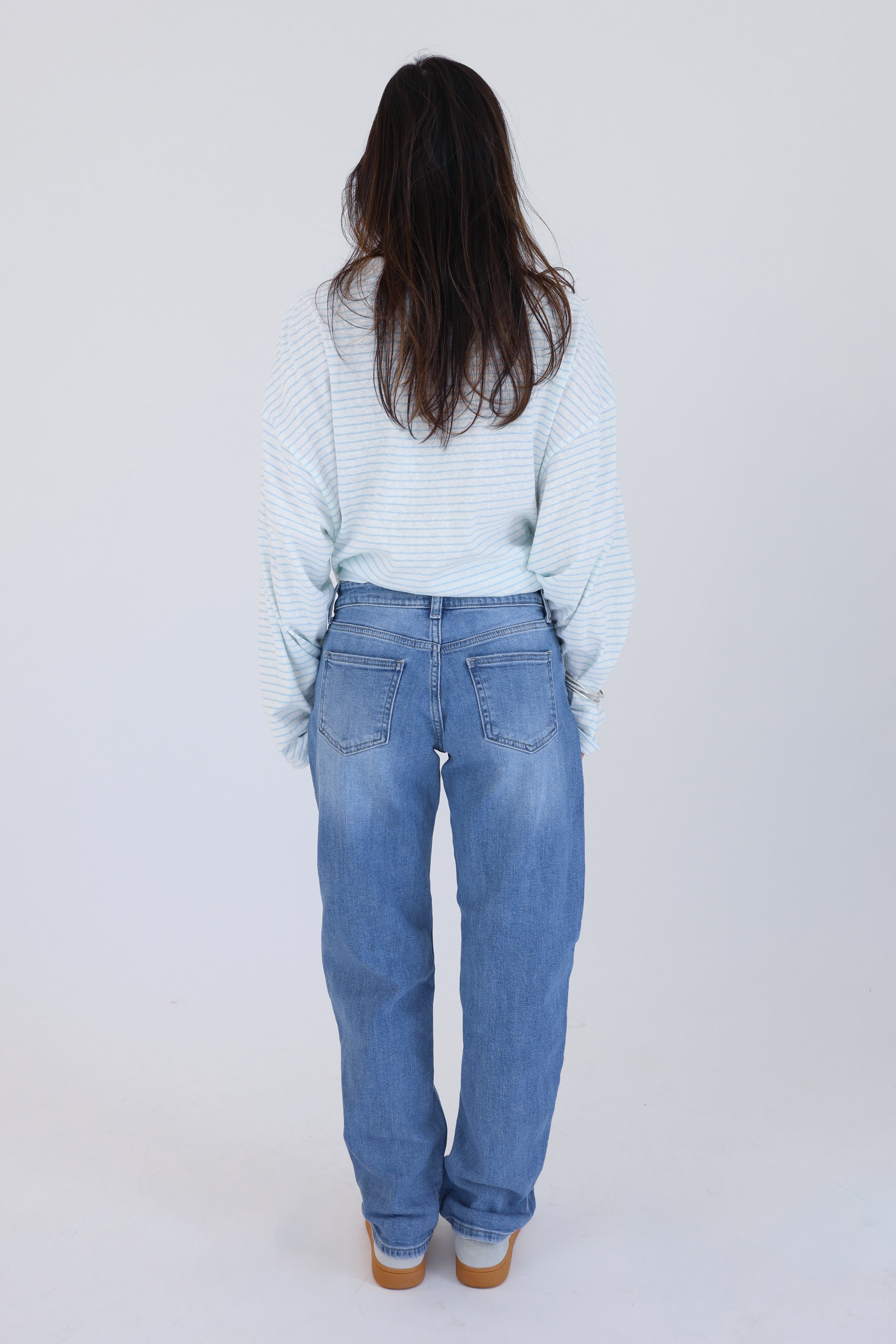 Person wearing light blue jeans and a striped shirt on a white background