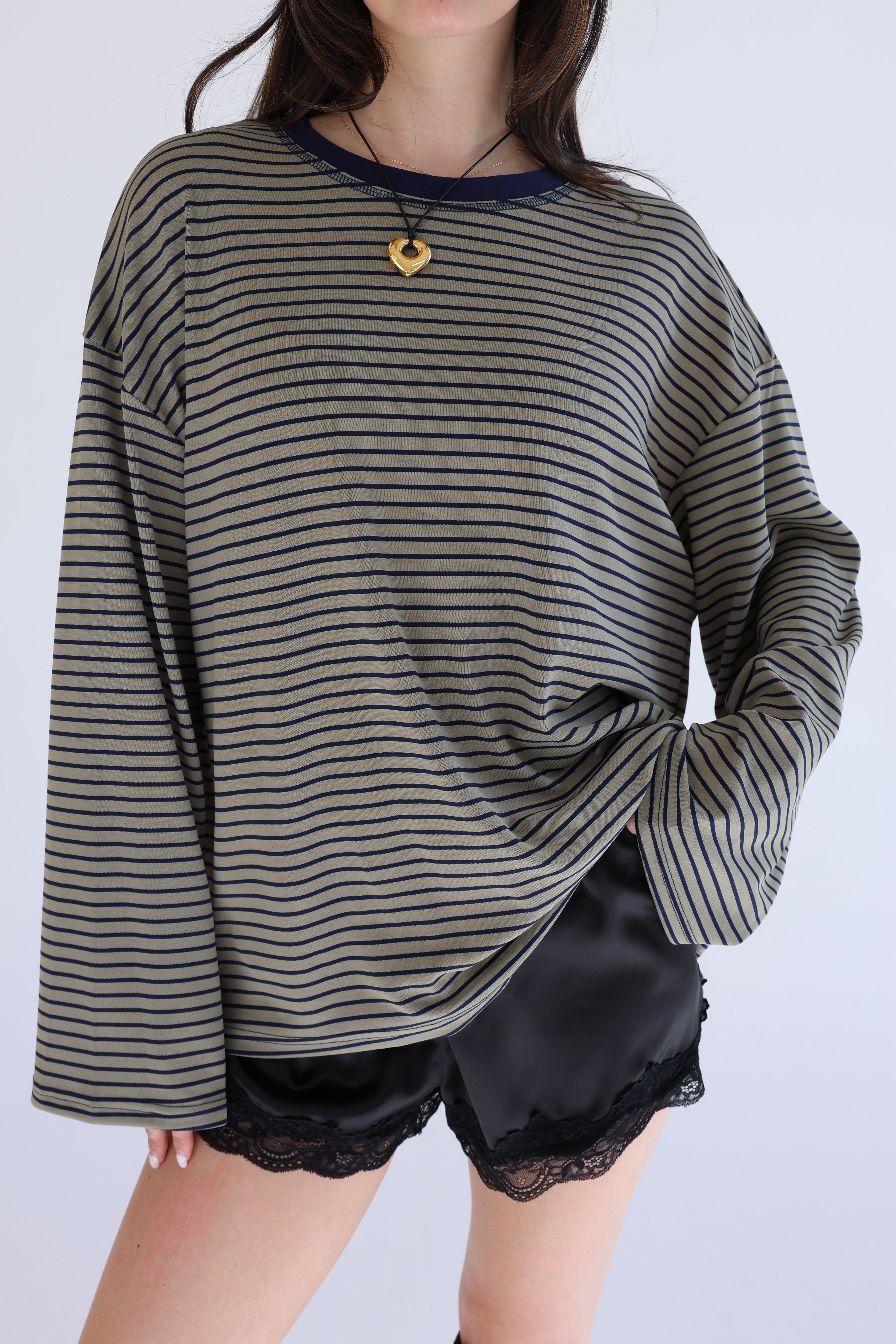 Person wearing a striped long-sleeve top and black satin shorts on a white background