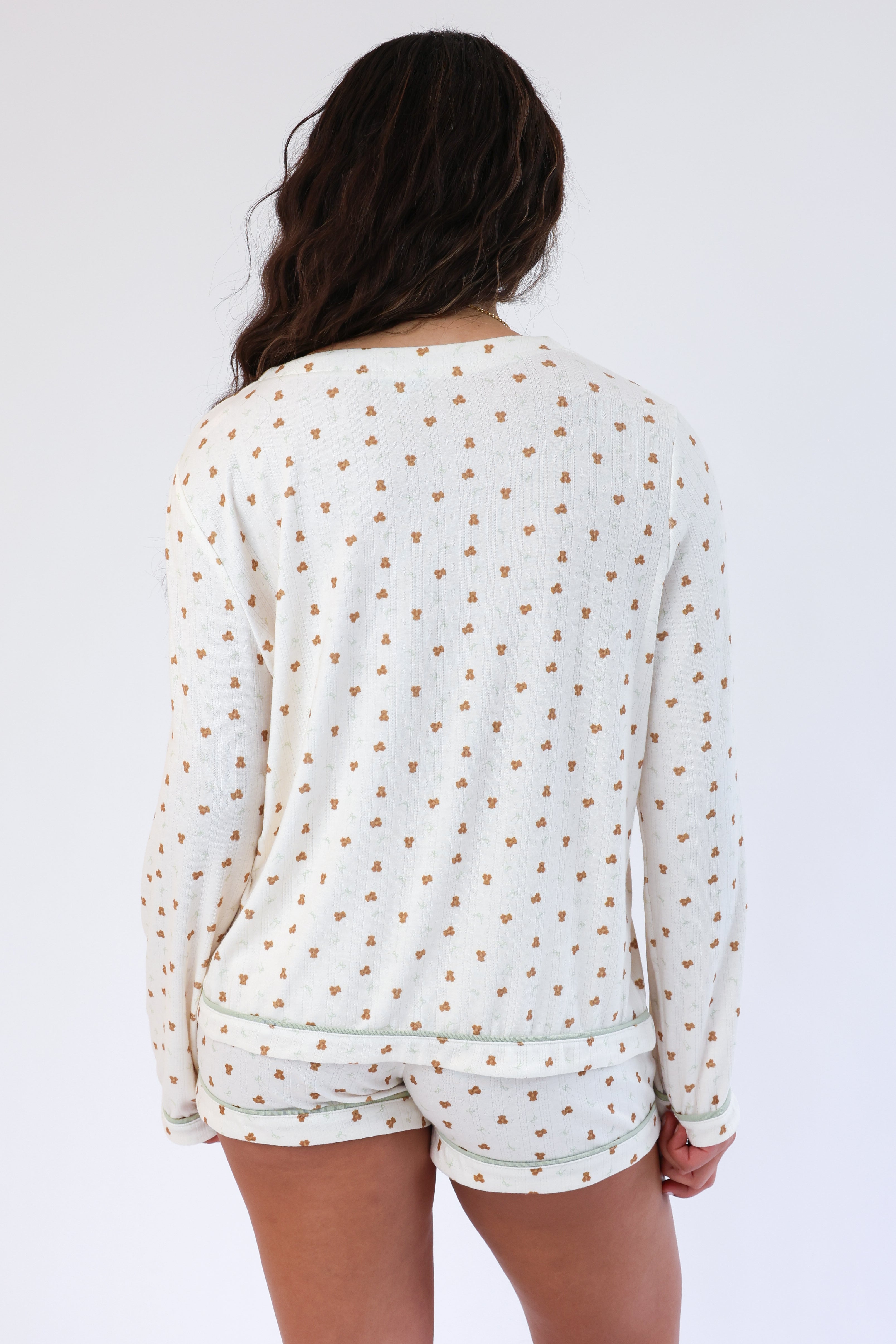 Person wearing a white long-sleeve top with small patterns and matching shorts on a white background