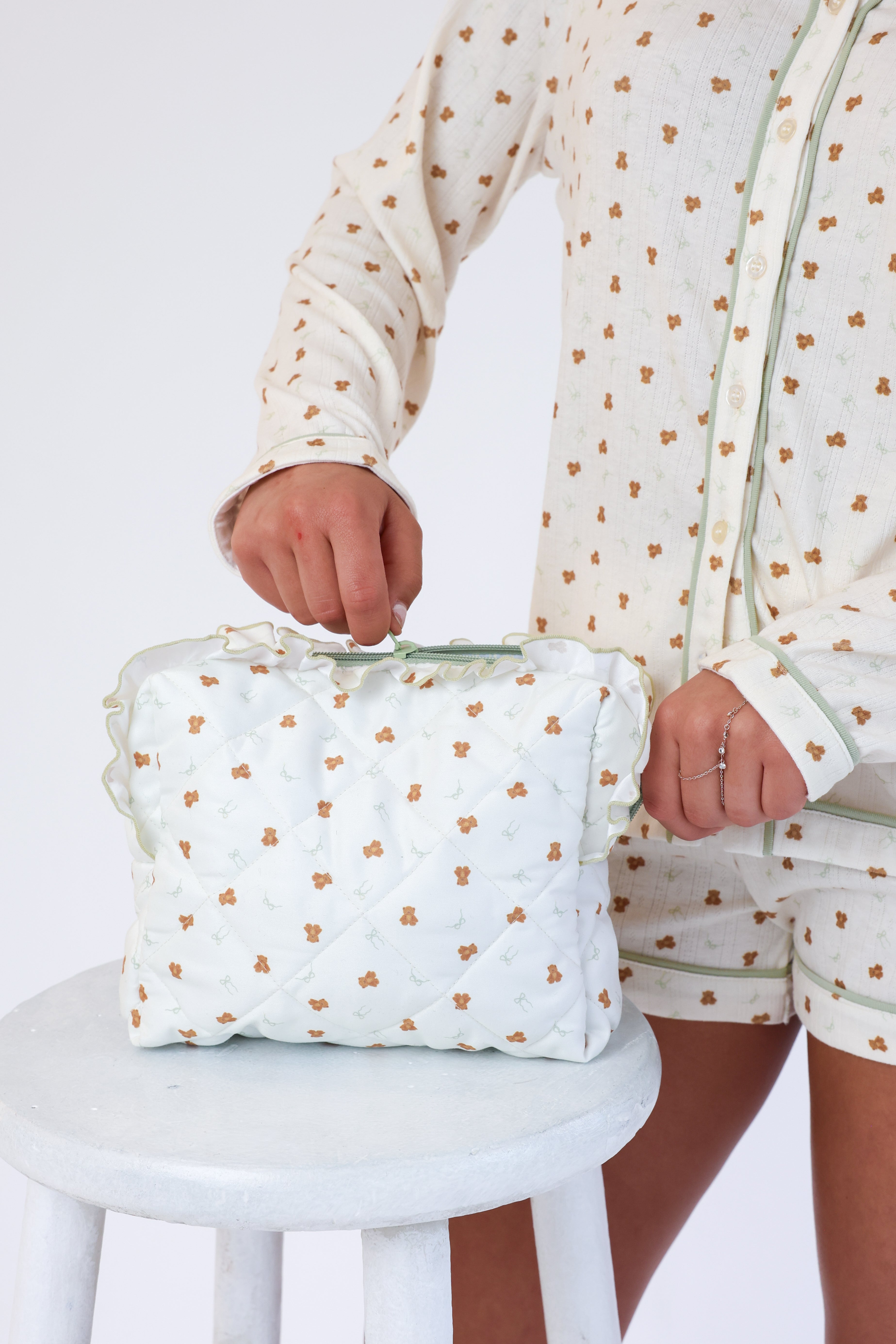Person holding a white bag with gold polka dots on a white background