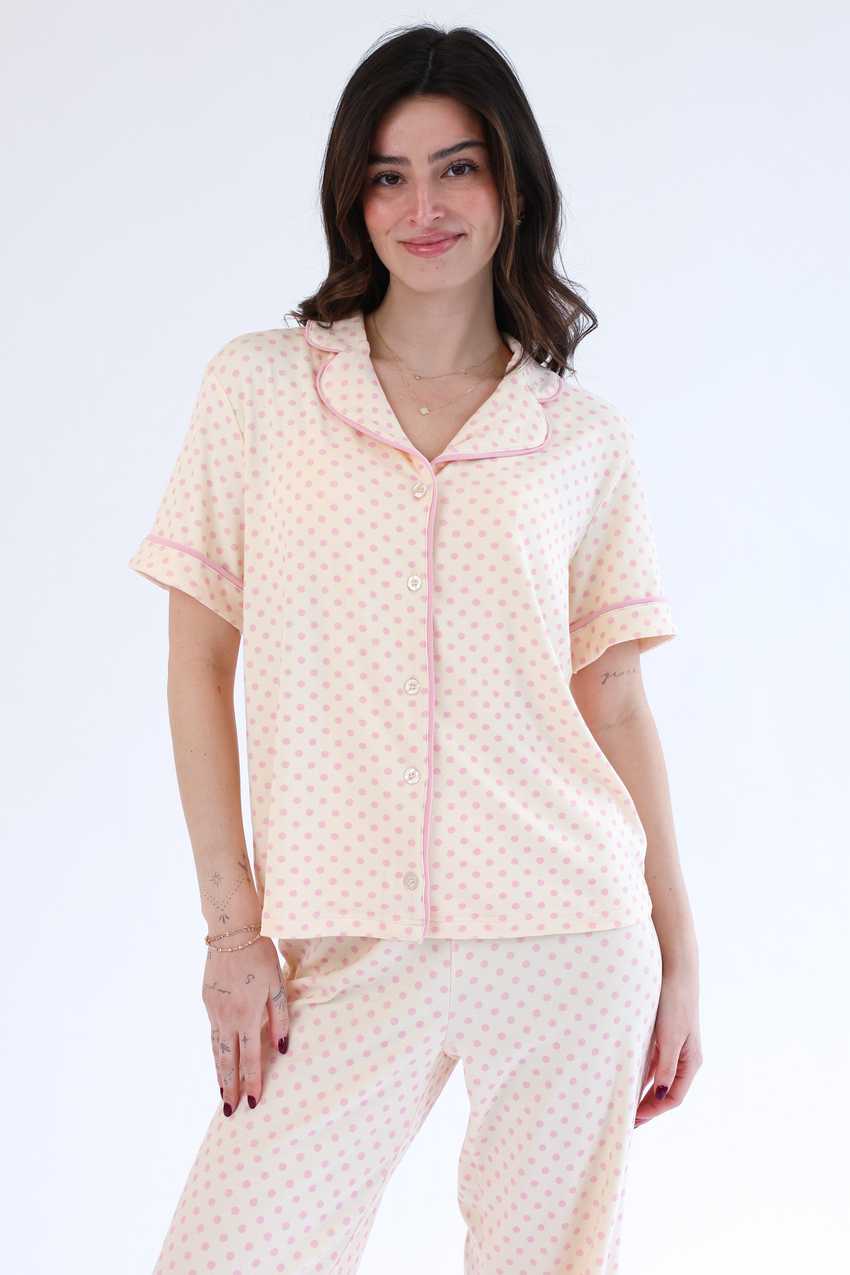 Woman wearing a light pink pajama set with a white background