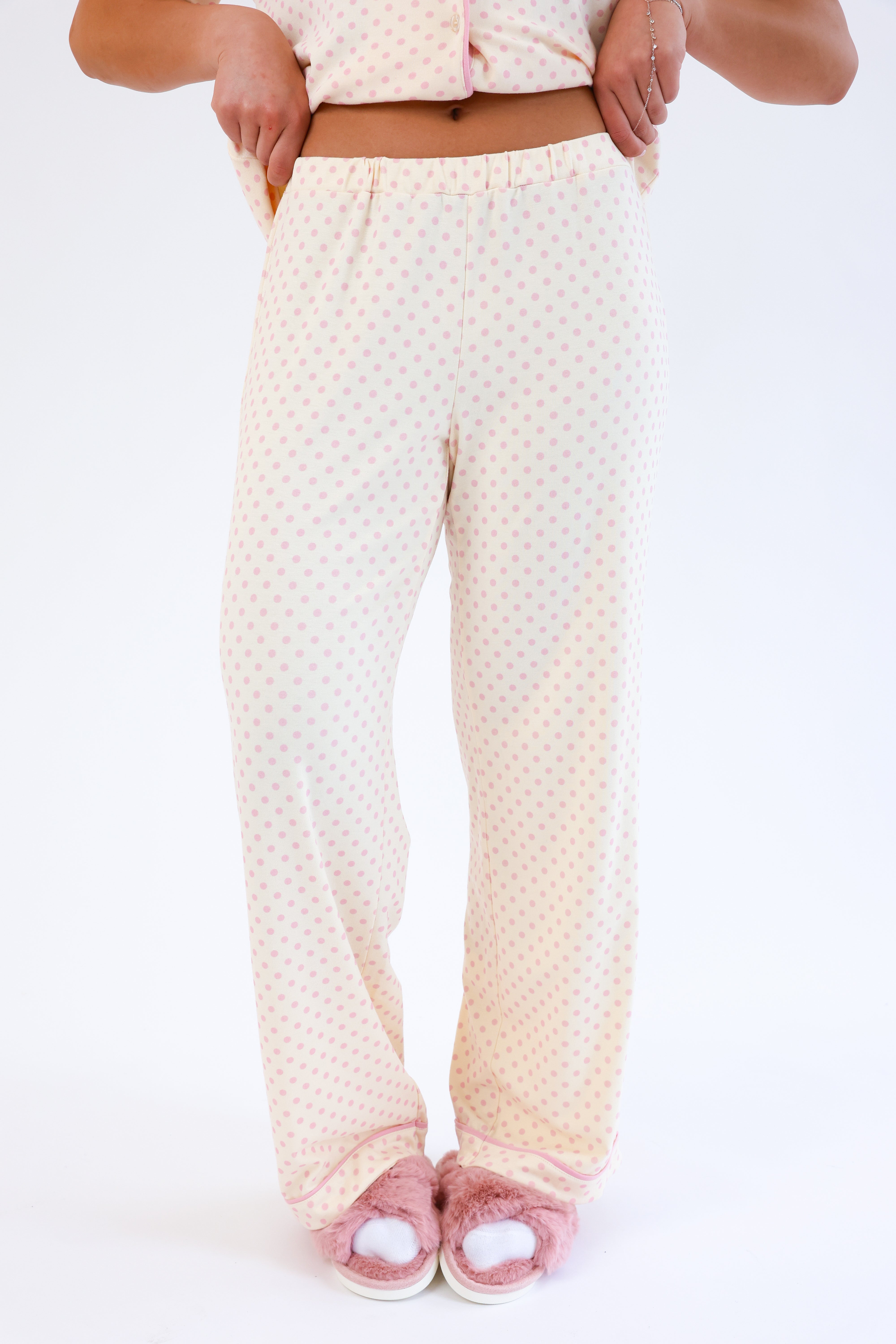 Person wearing cream-colored pajama pants with a subtle pattern on a white background