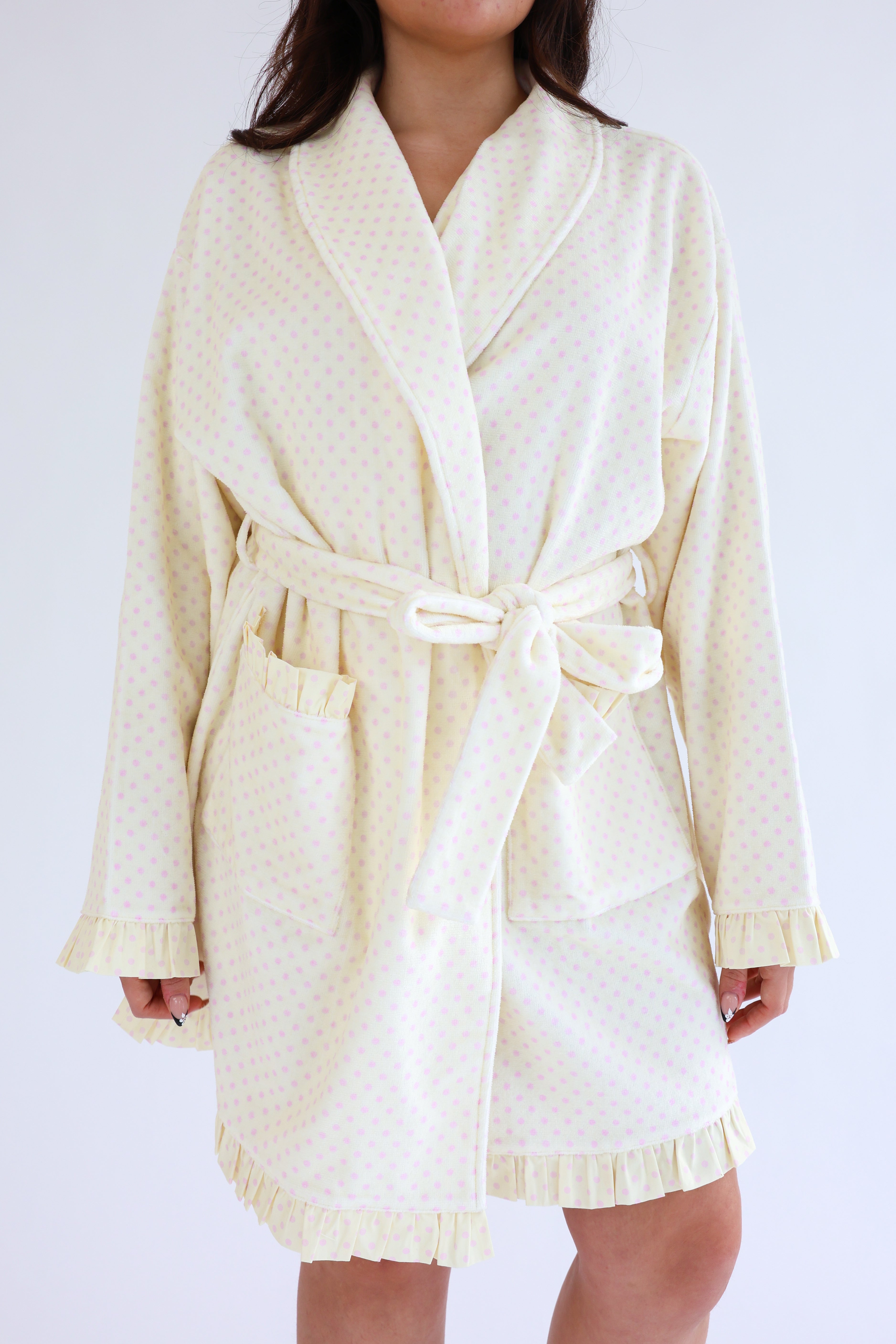 Person wearing a cream-colored robe against a white background