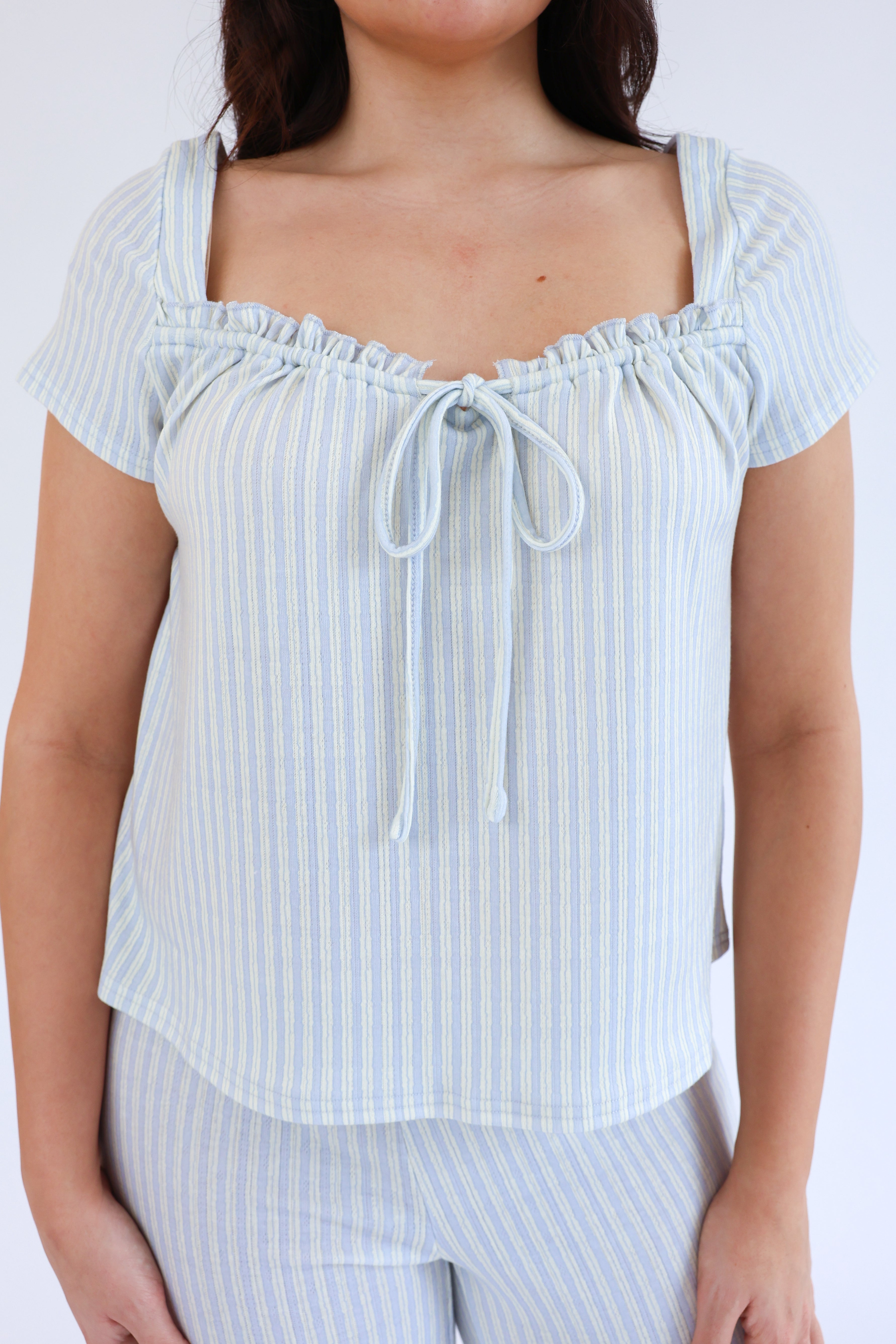 Light blue striped top worn by a person on a white background