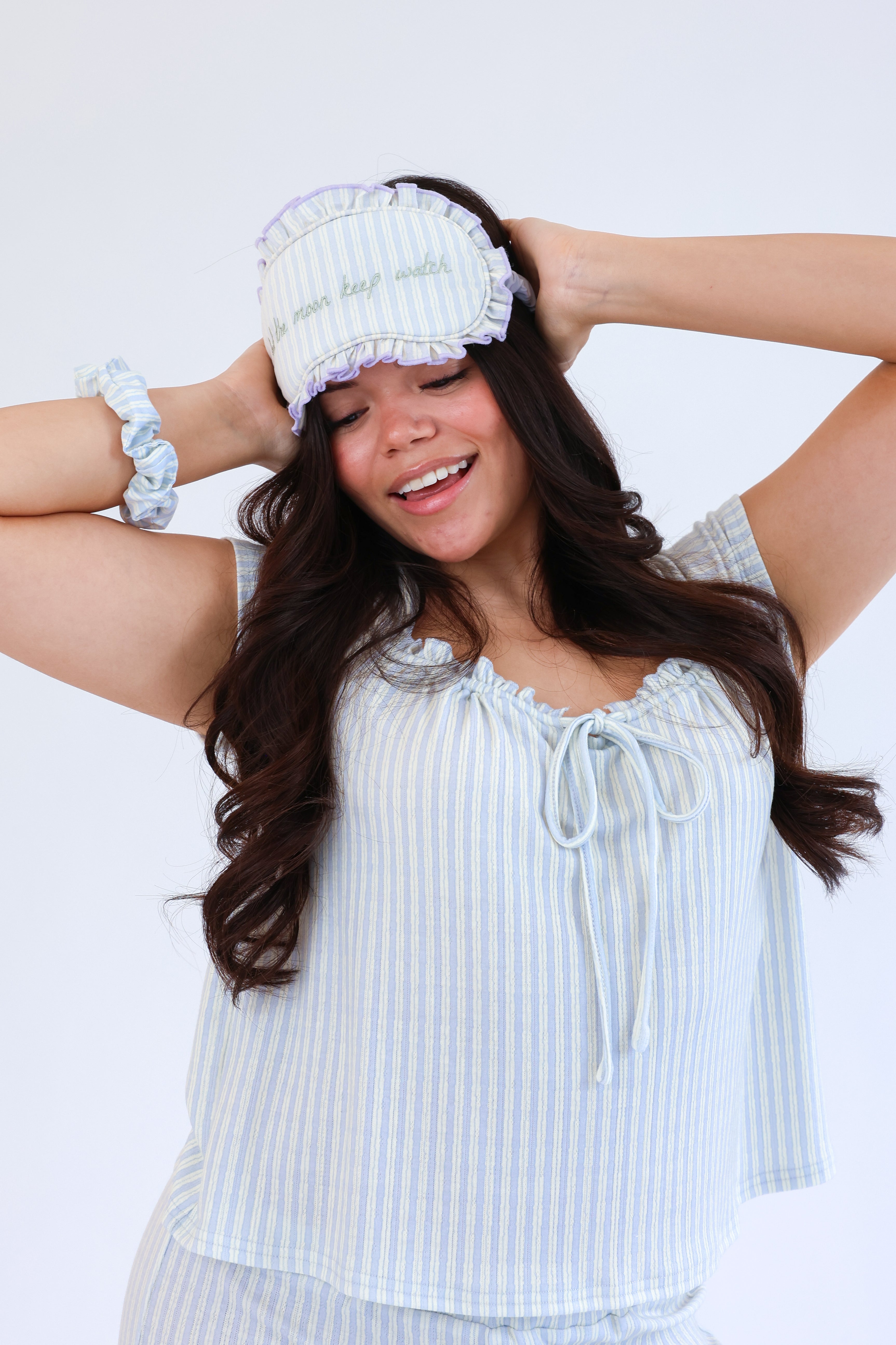 Woman wearing a light blue striped top and matching headband against a white background