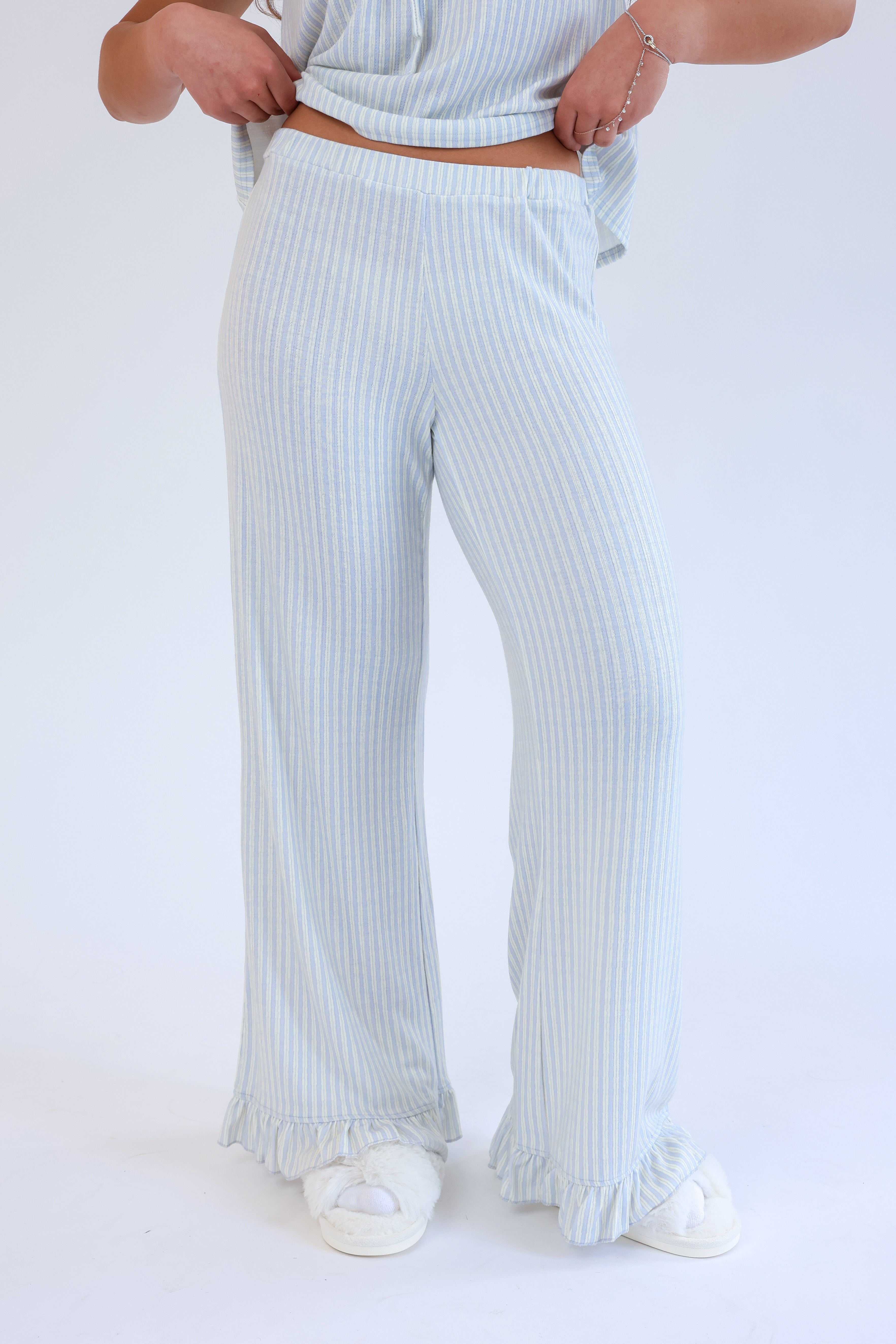 Person wearing light blue striped pants on a white background