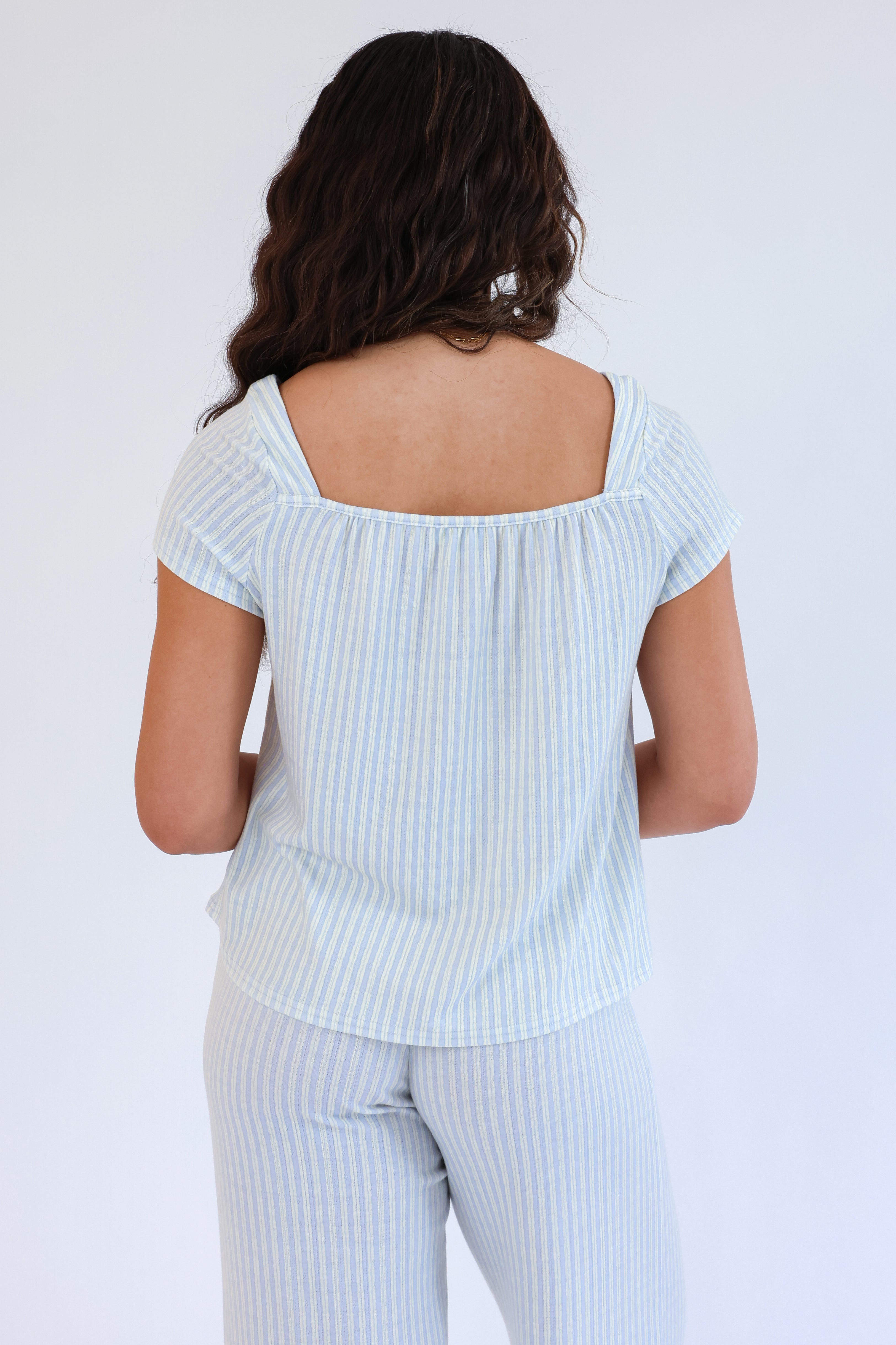 Woman wearing a light blue striped outfit against a white background