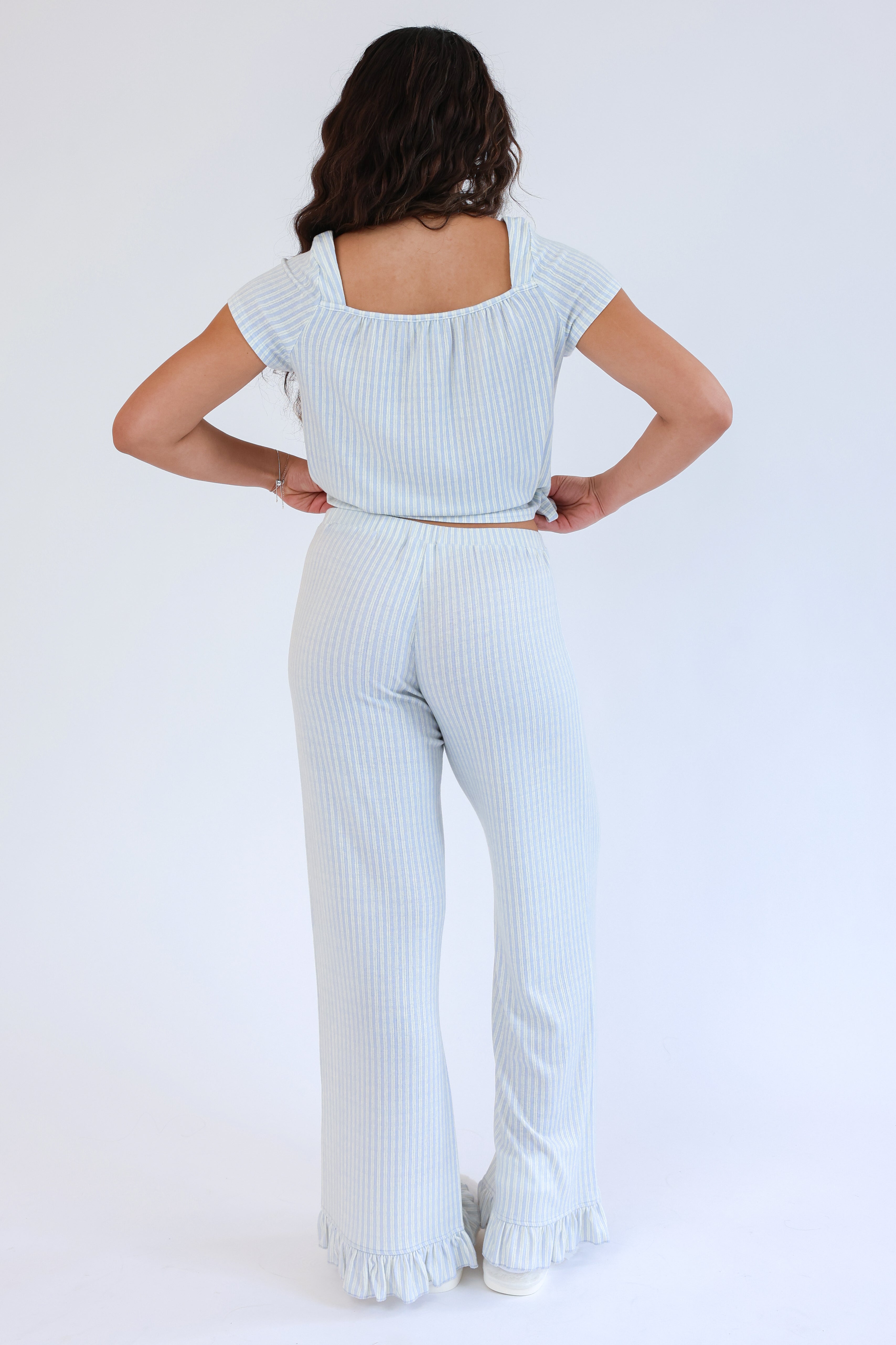 Woman wearing a light blue ribbed top and pants on a white background