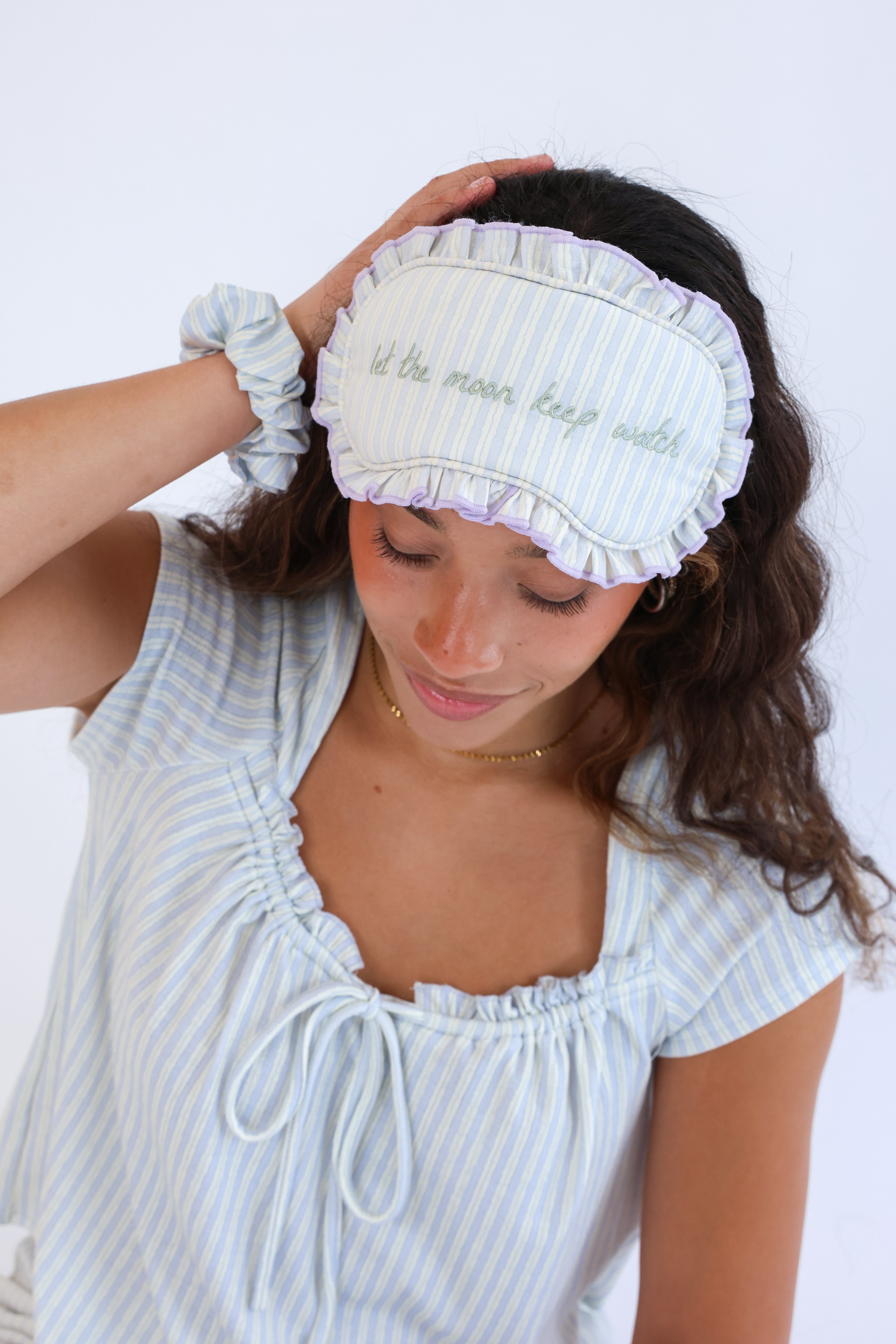 Woman wearing a light blue sleep mask with text on a white background
