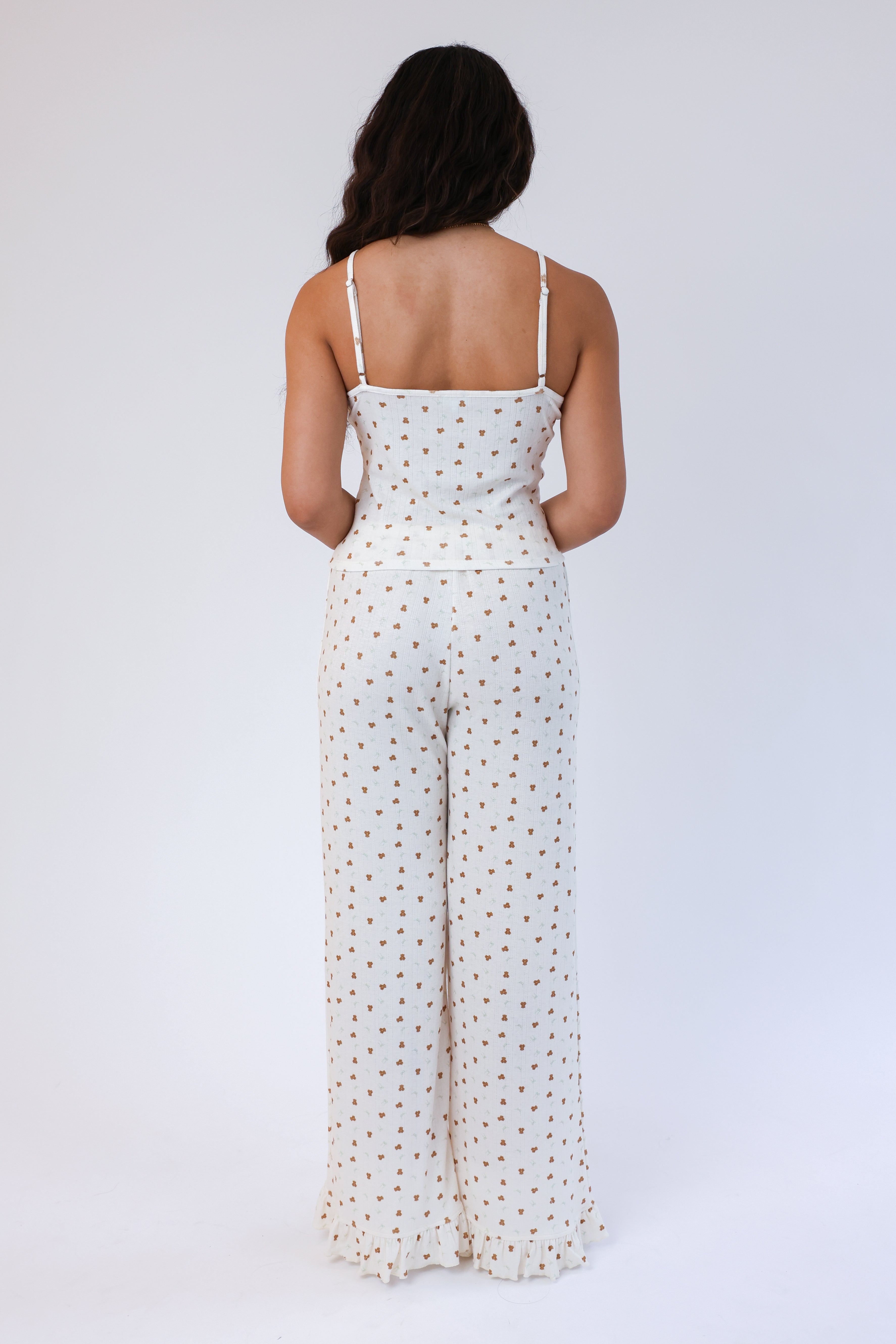 Woman wearing a white polka dot jumpsuit on a plain background