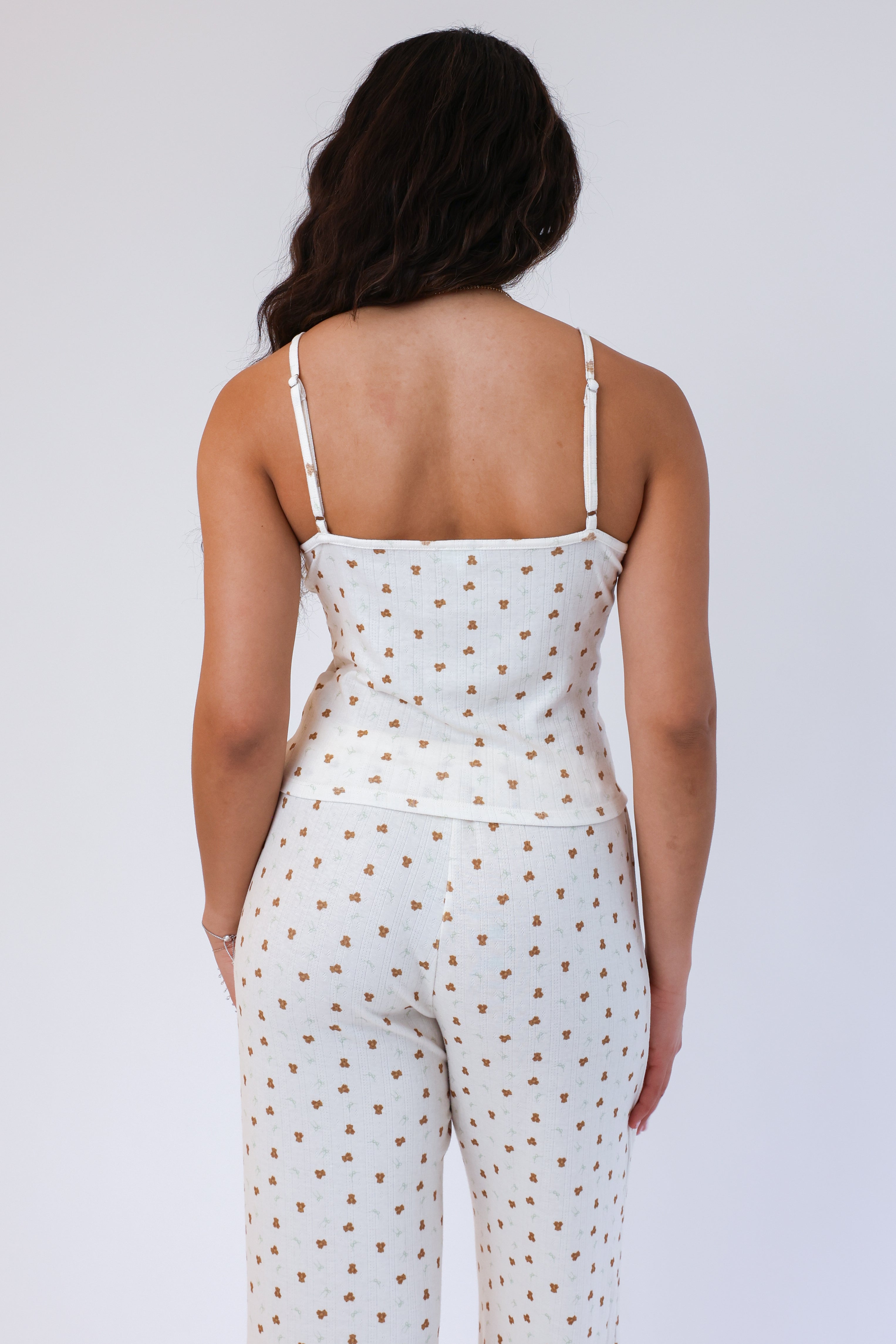 Woman wearing a white polka dot jumpsuit on a plain background