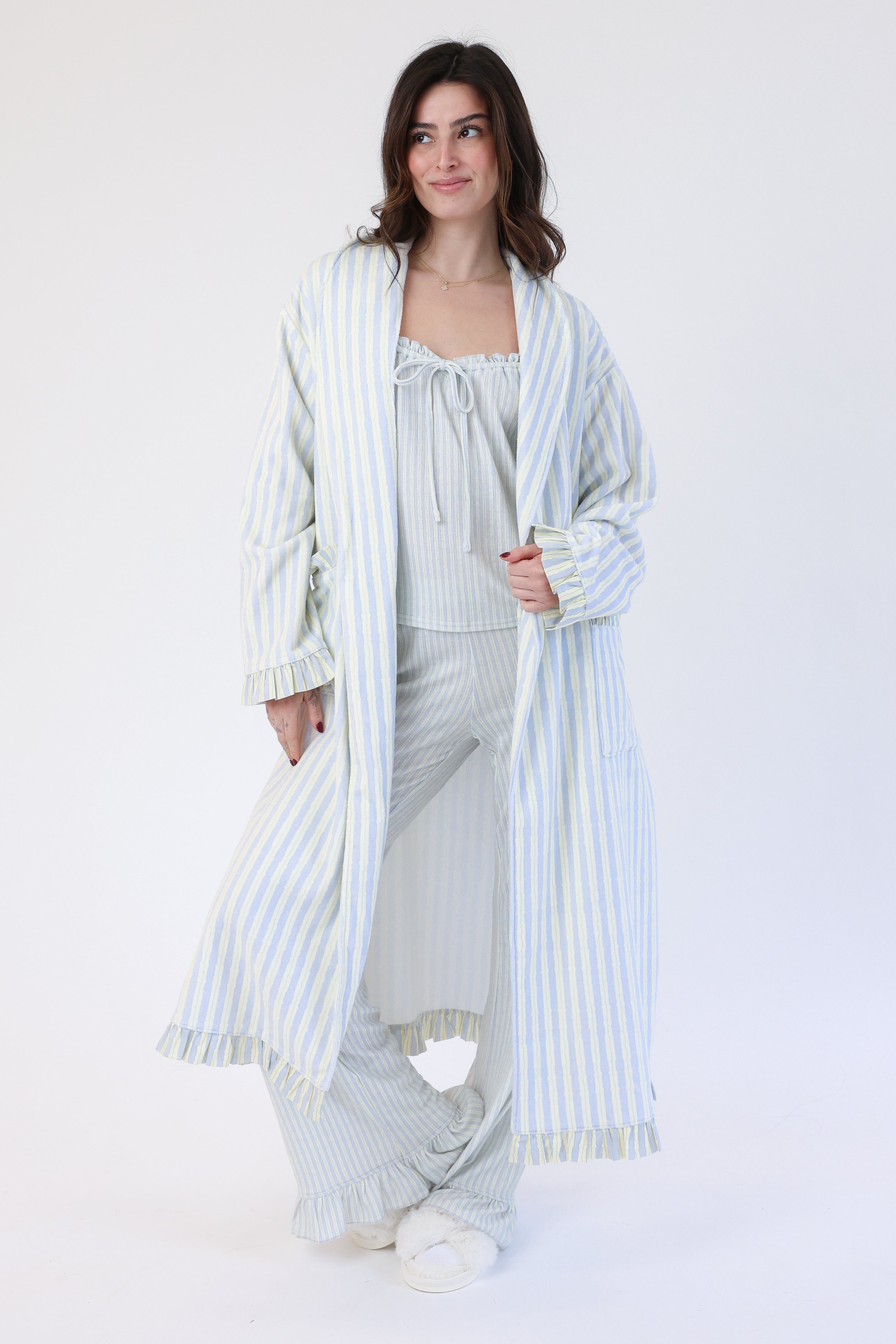 Woman wearing a striped pajama set with a long robe on a white background