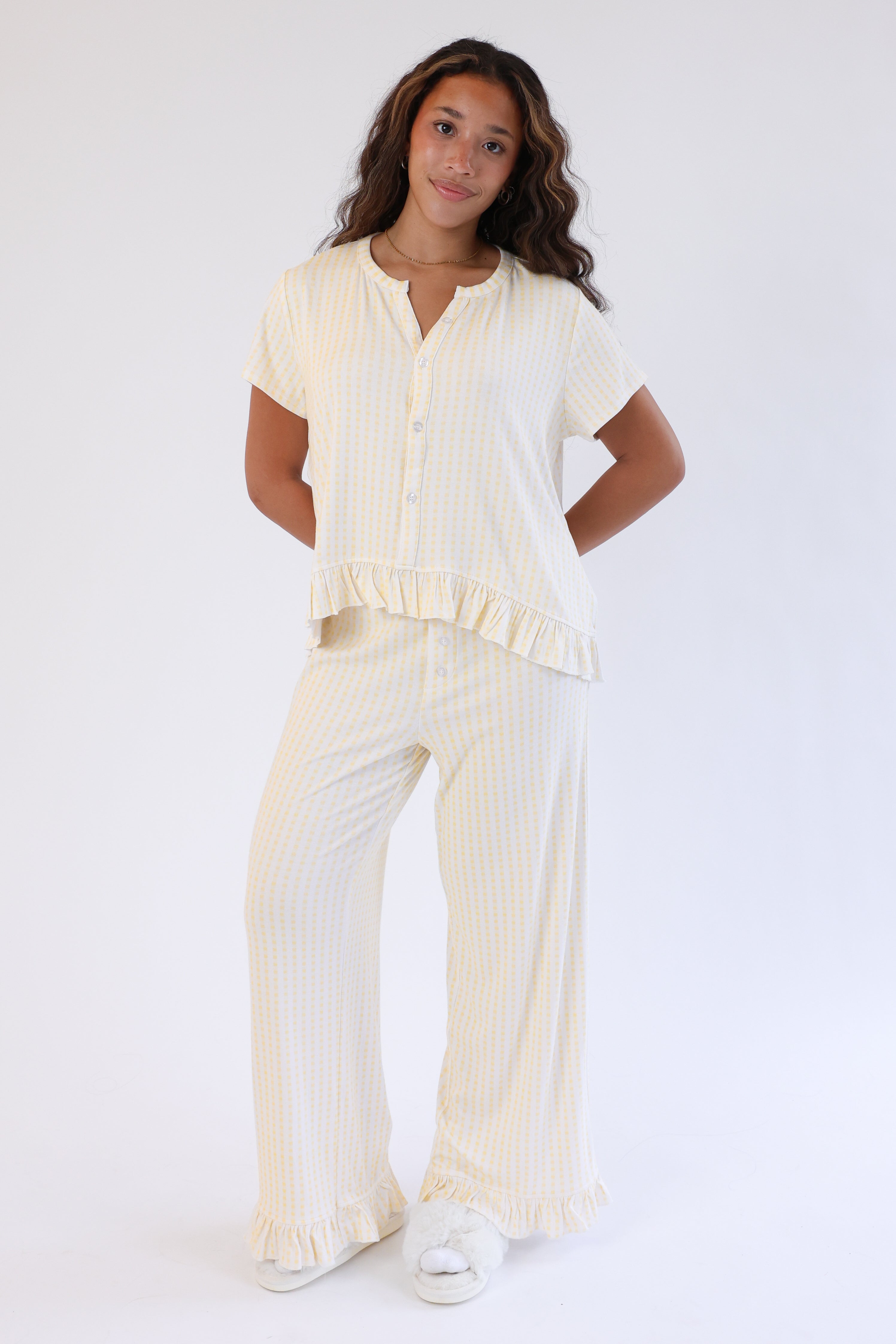 Woman wearing a cream-colored outfit with a top and pants on a white background