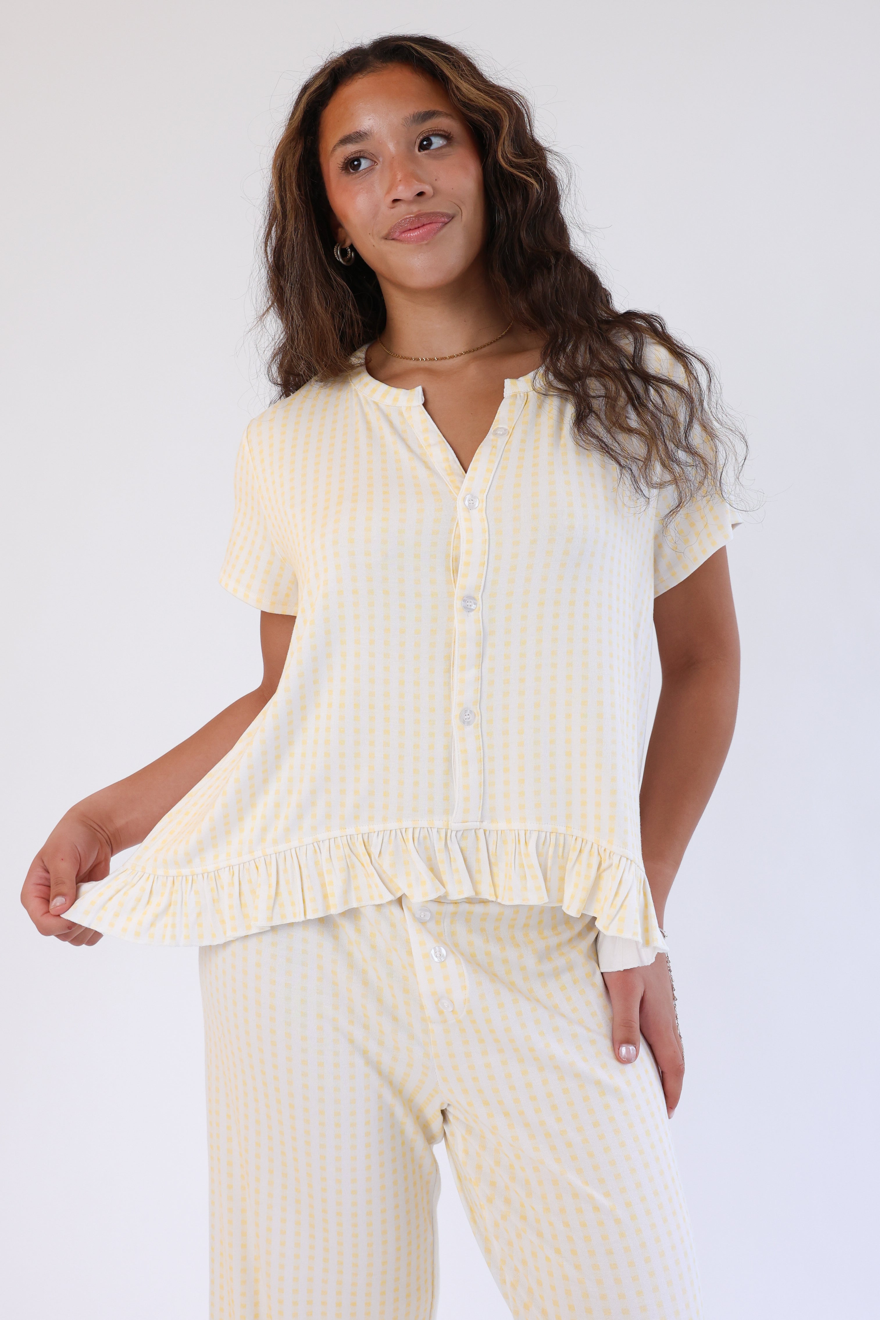 Woman wearing a light yellow blouse and pants on a white background