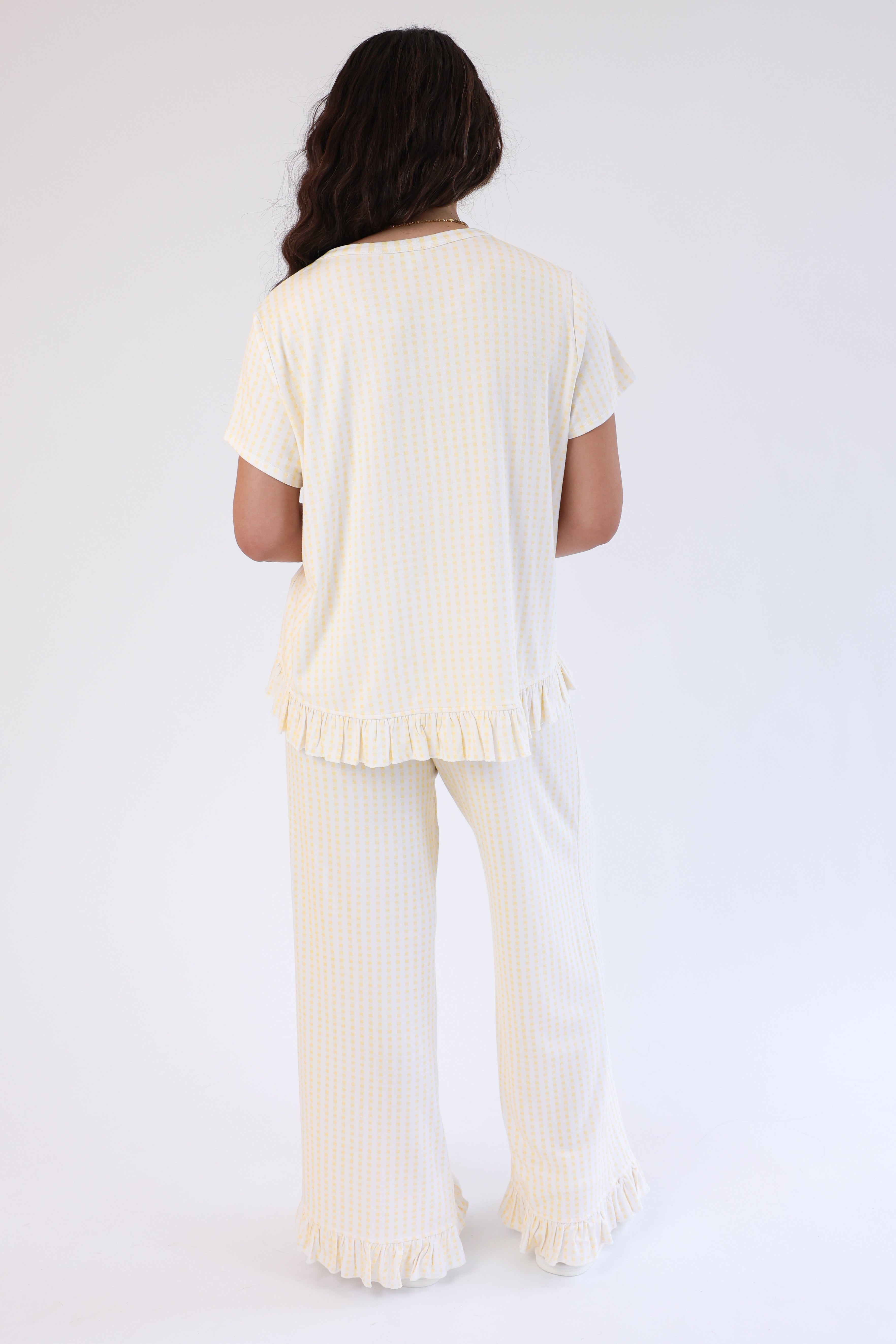 Woman wearing a cream-colored outfit with ruffled details on a white background