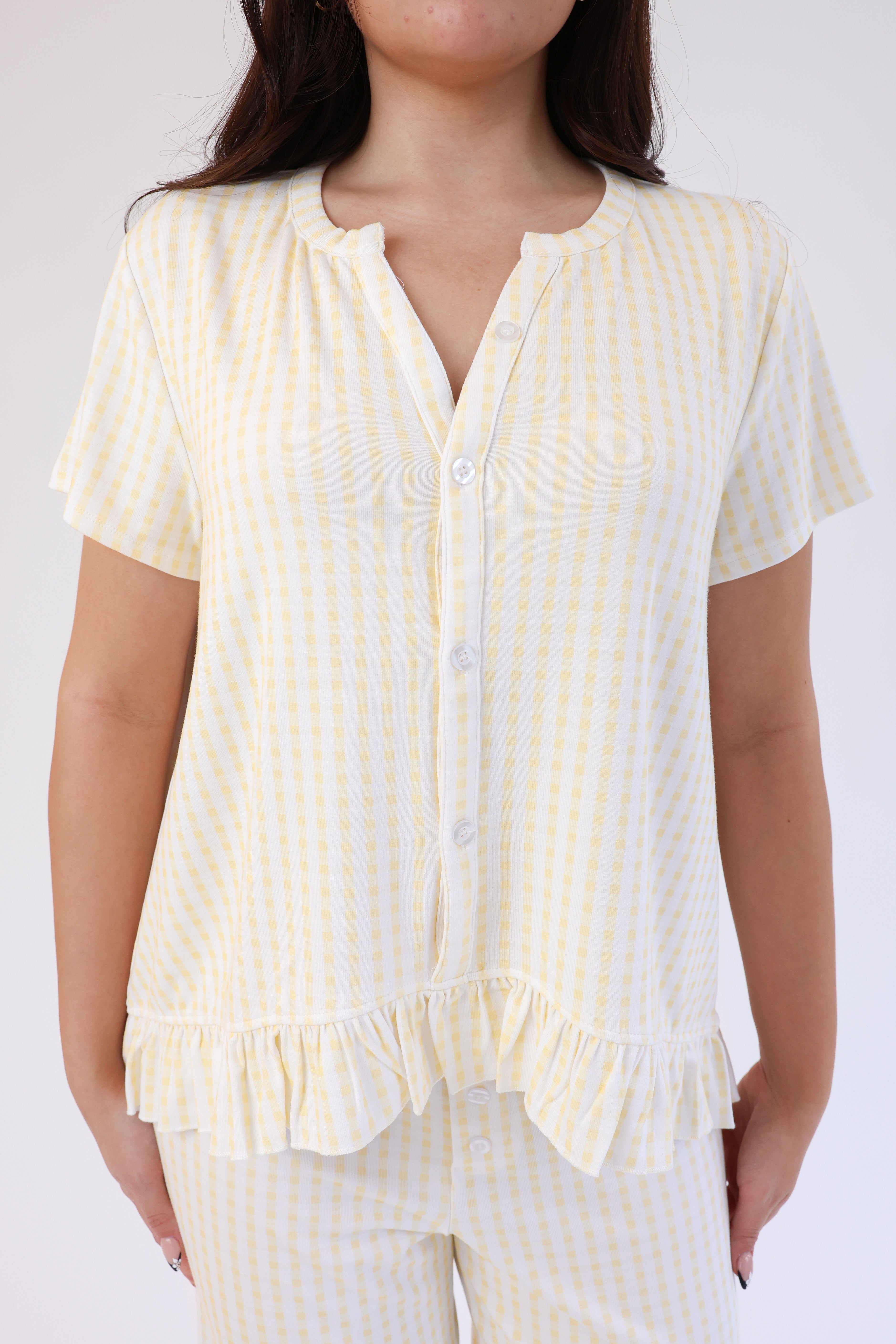 Woman wearing a yellow and white striped pajama set against a plain background
