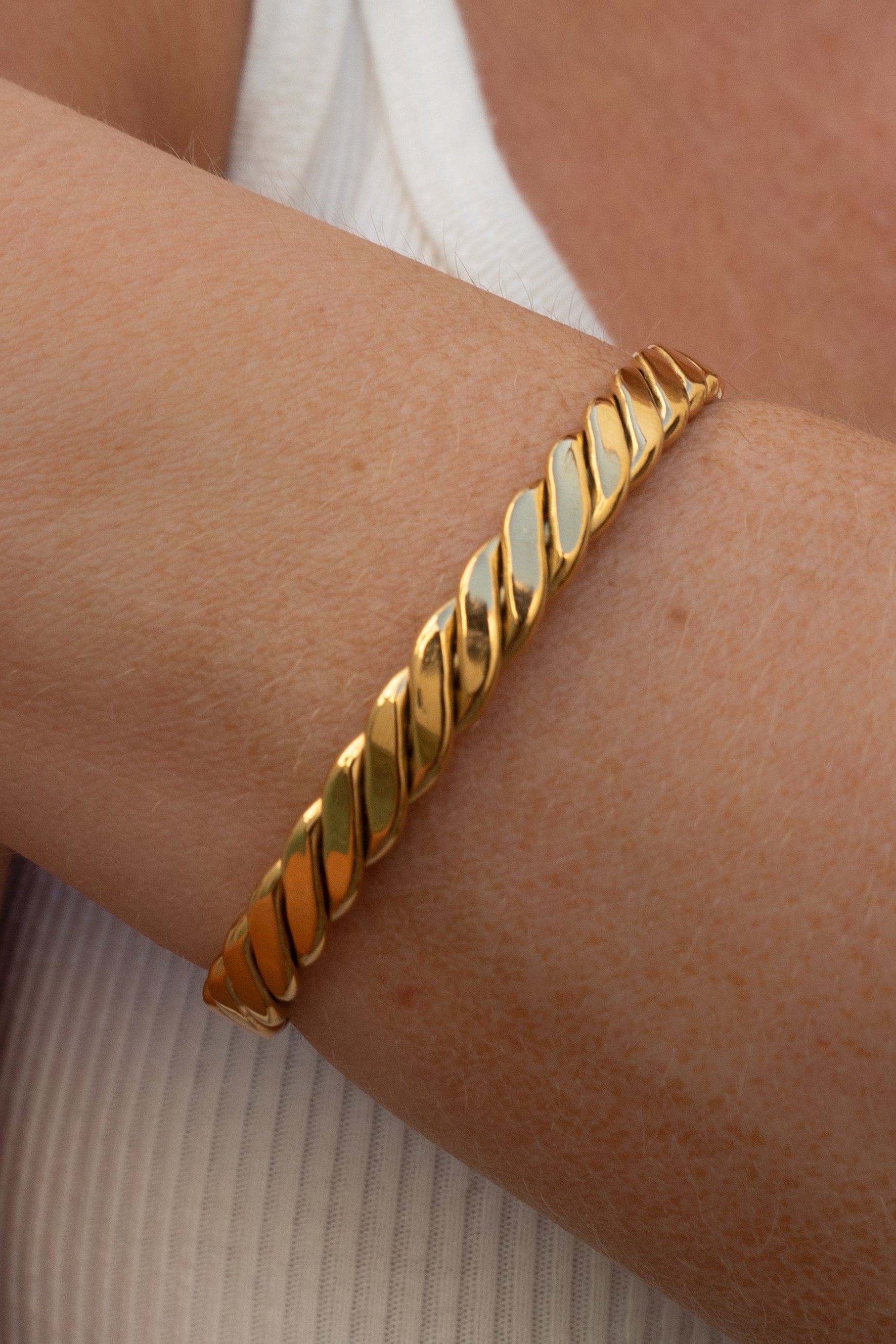 Gold bracelet on a person's wrist with a neutral background