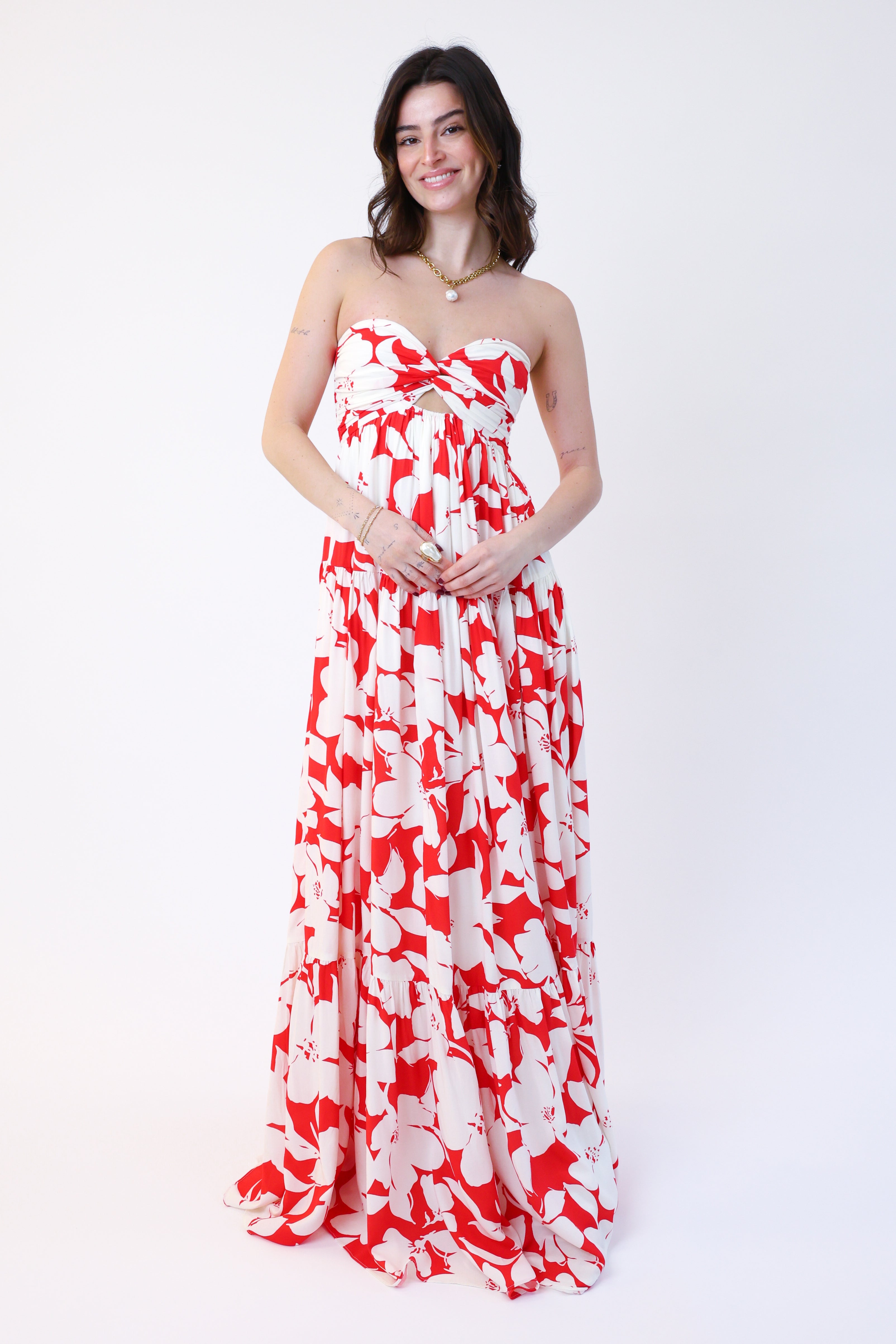 Woman wearing a strapless red and white floral dress on a white background