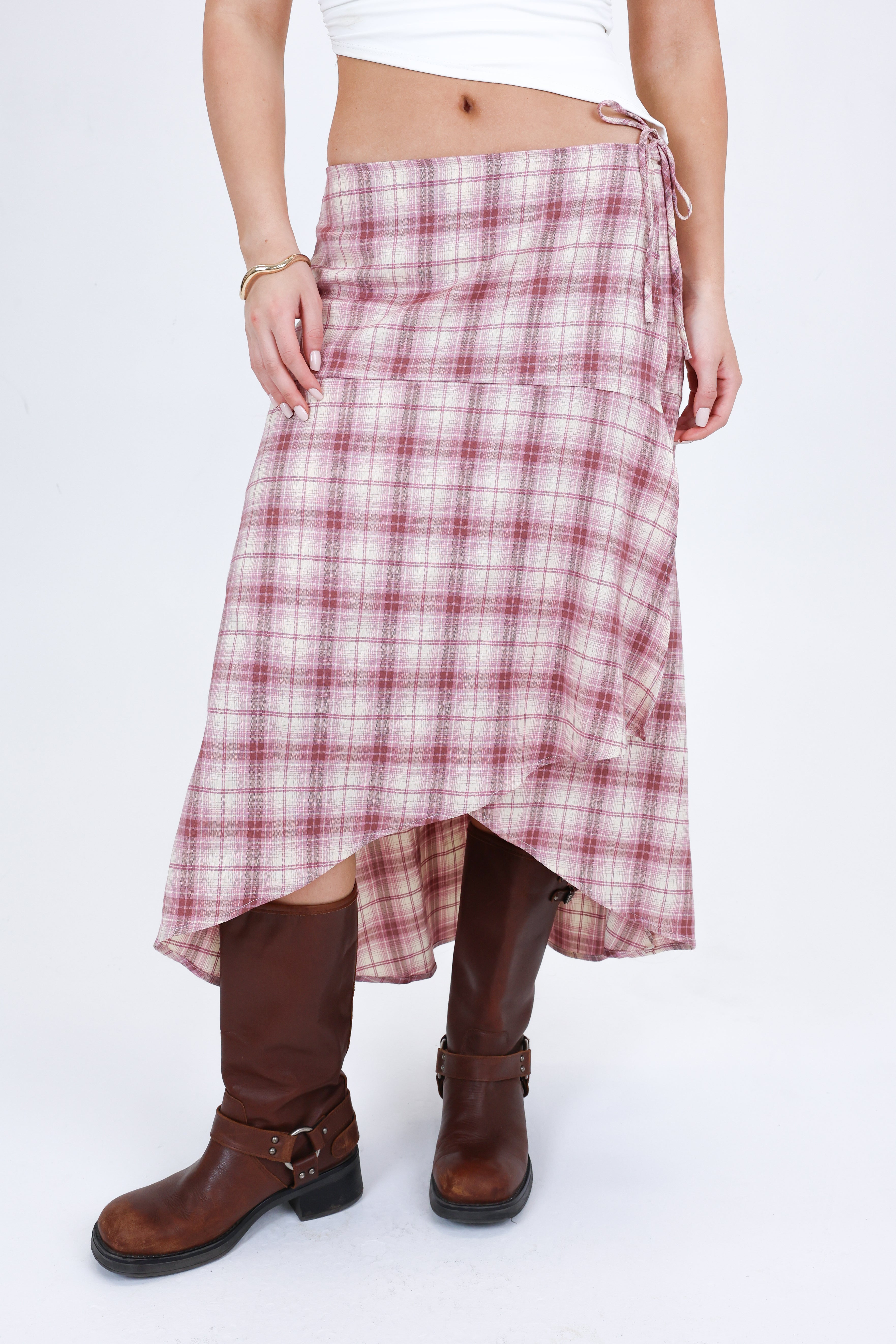 Person wearing a plaid skirt and brown boots on a white background