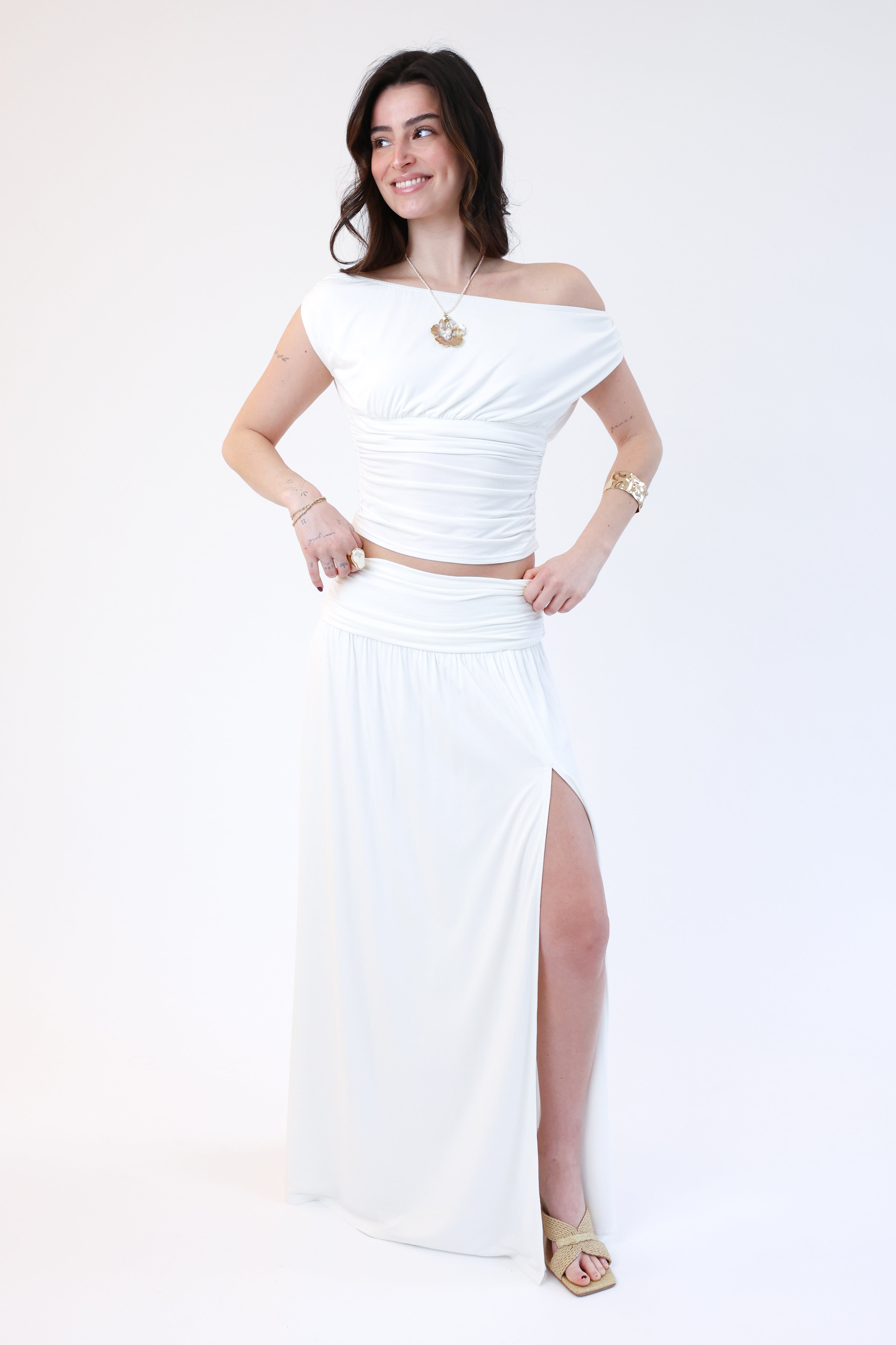 Woman wearing a white off-shoulder top and long skirt on a white background