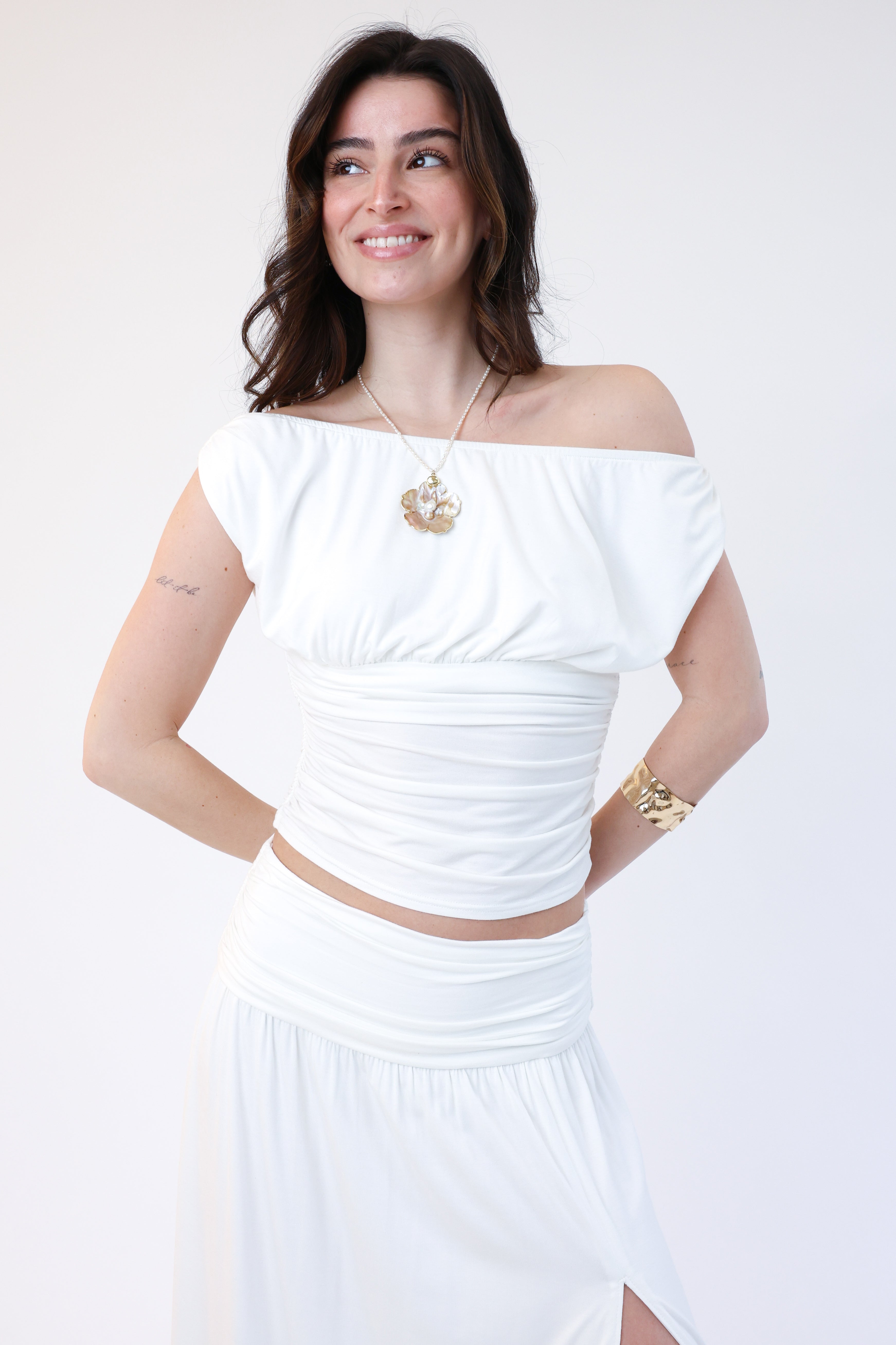 Woman wearing a white off-shoulder top and skirt on a white background