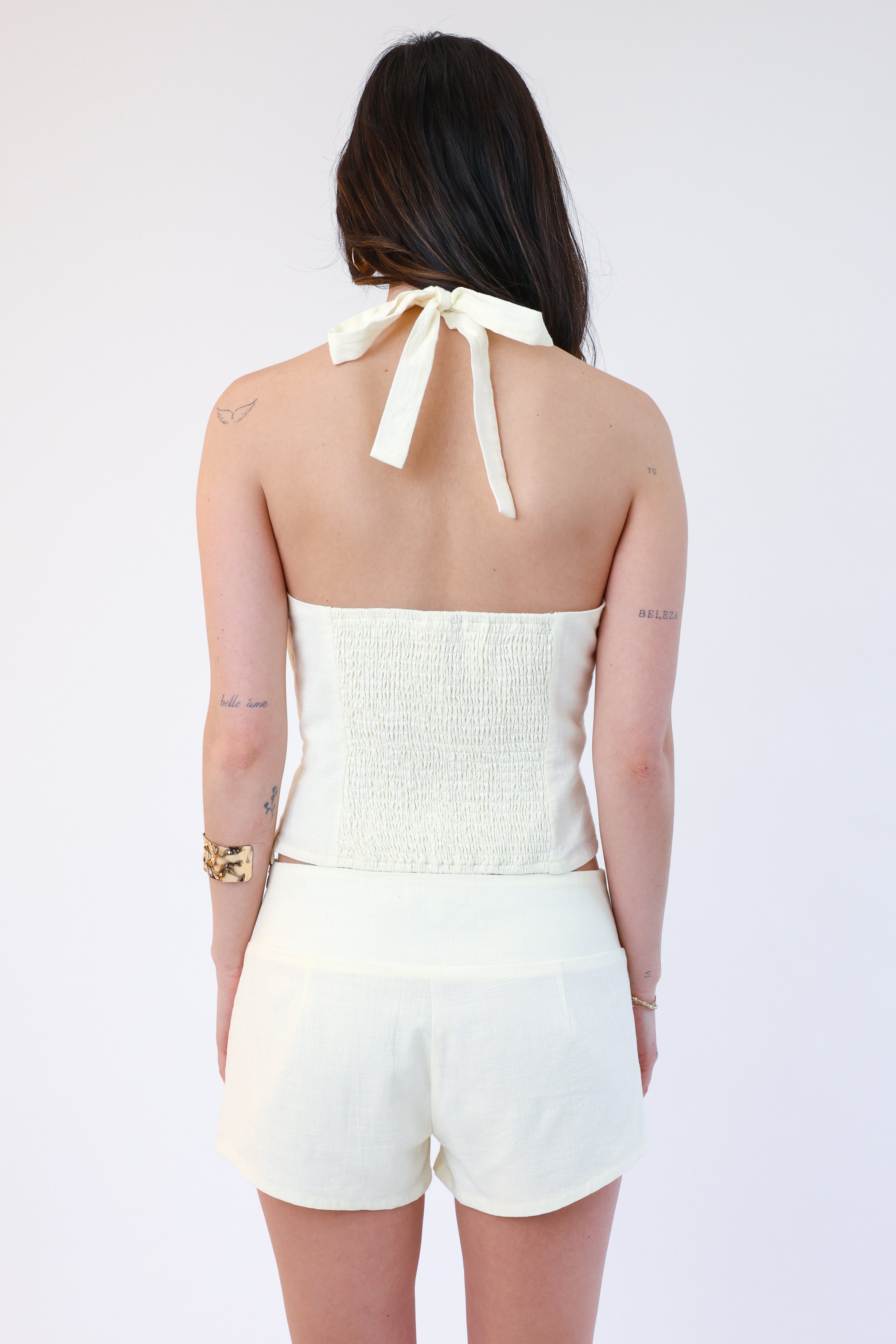 Woman wearing a white strapless top and shorts set with a bow detail on a white background
